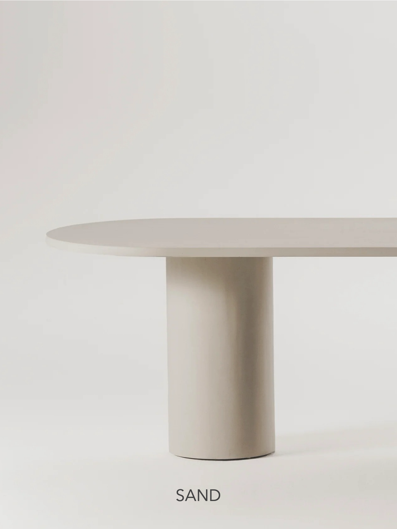 The Gio Dining Table by MarlotBaus features a minimalist oval shape with a cylindrical microcement base in light beige "SAND," set against a plain white background.