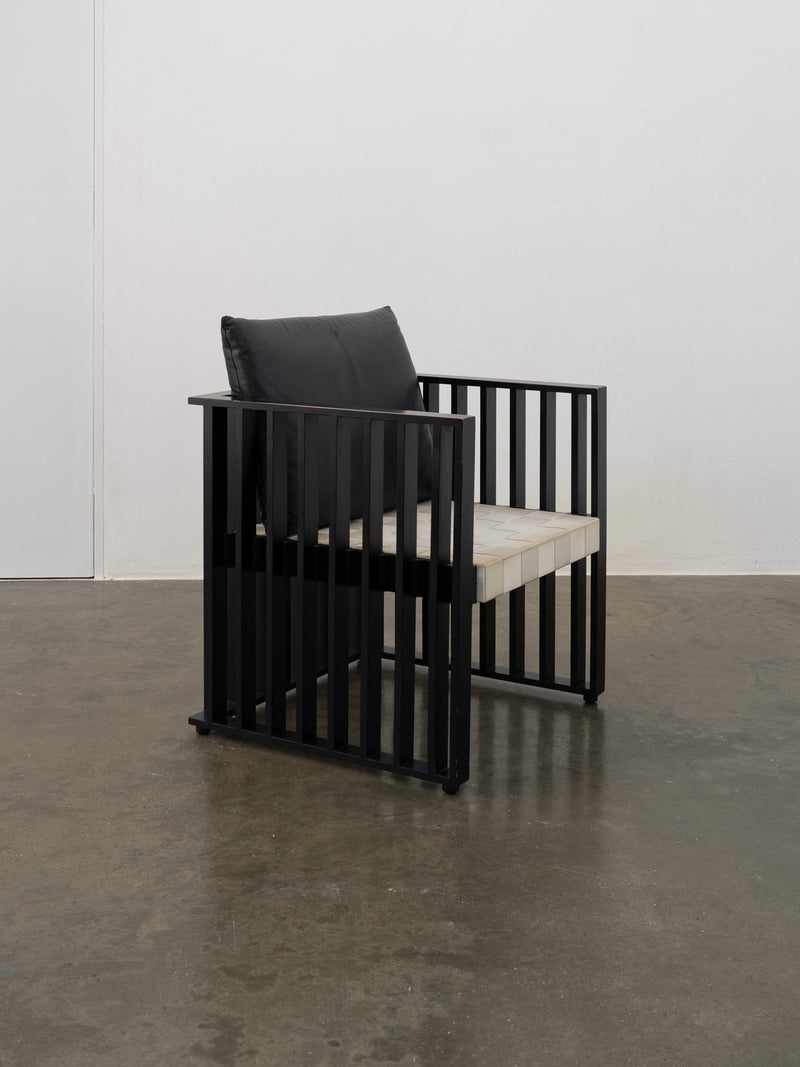 Black geometric armchair with vertical slats and cream seat cushion