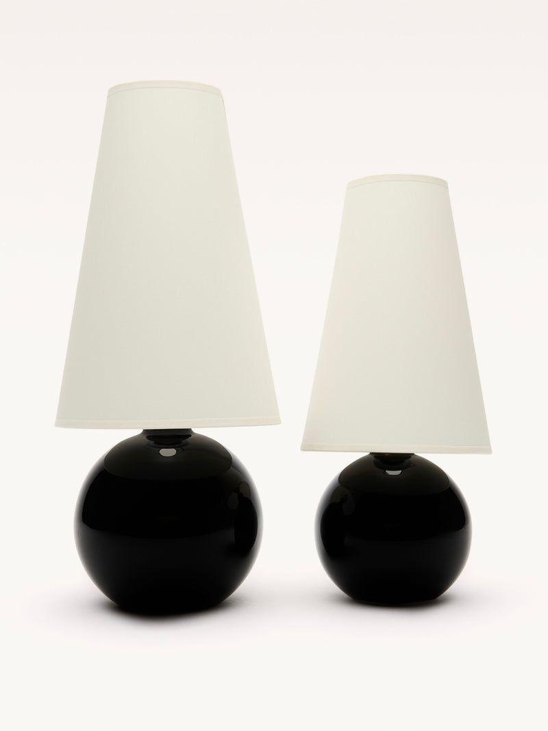 Two Galerie MLS Large Black Opalin Glass Lamps with spherical bases and white conical lampshades stand side by side against a plain background, the left lamp featuring a brass ring is slightly taller.