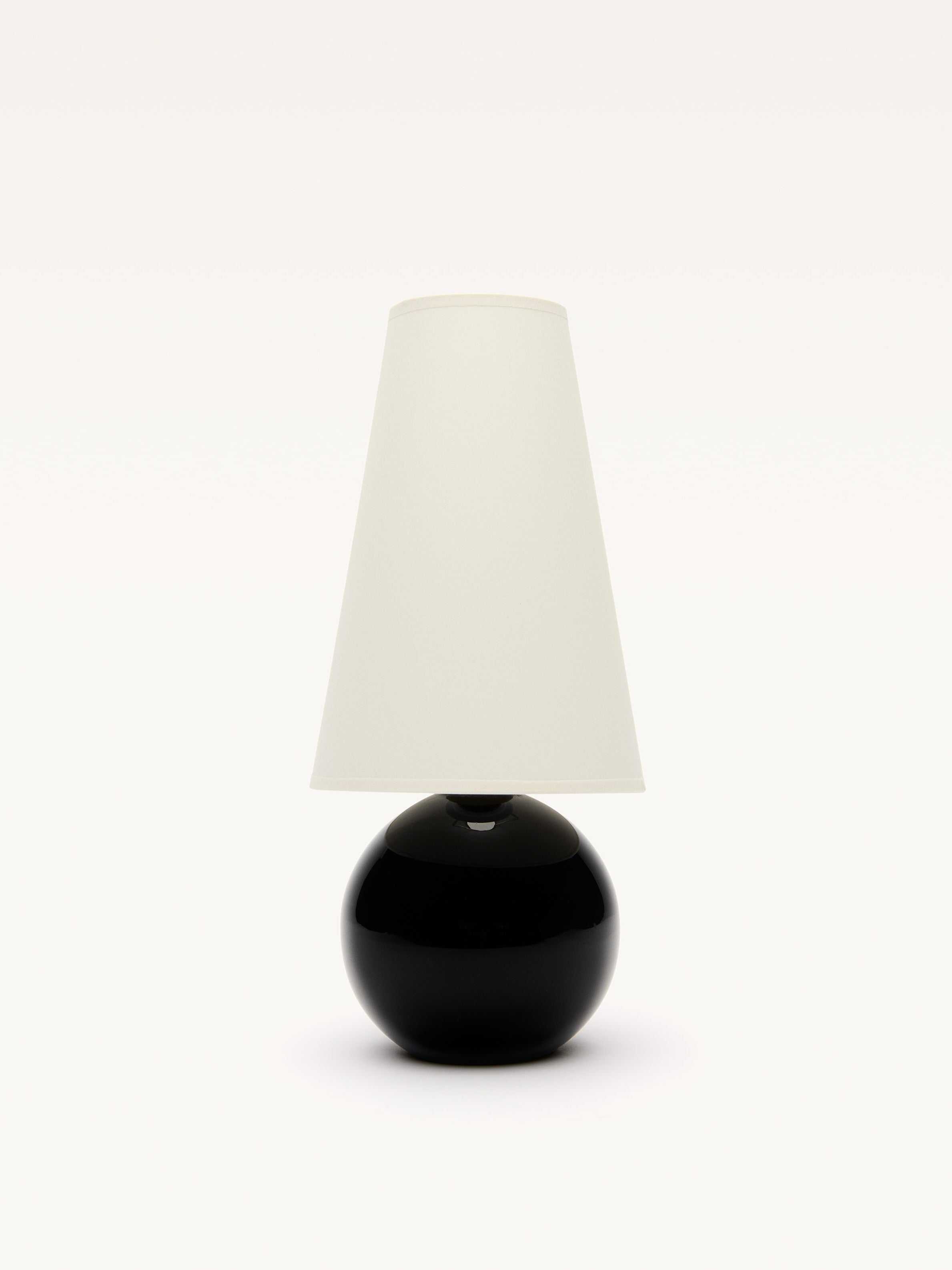 Against a plain white background, the Galerie MLS Small Black Opalin Glass Lamp features a round black base and tall conical white shade, reminiscent of Jacques Adnet style.