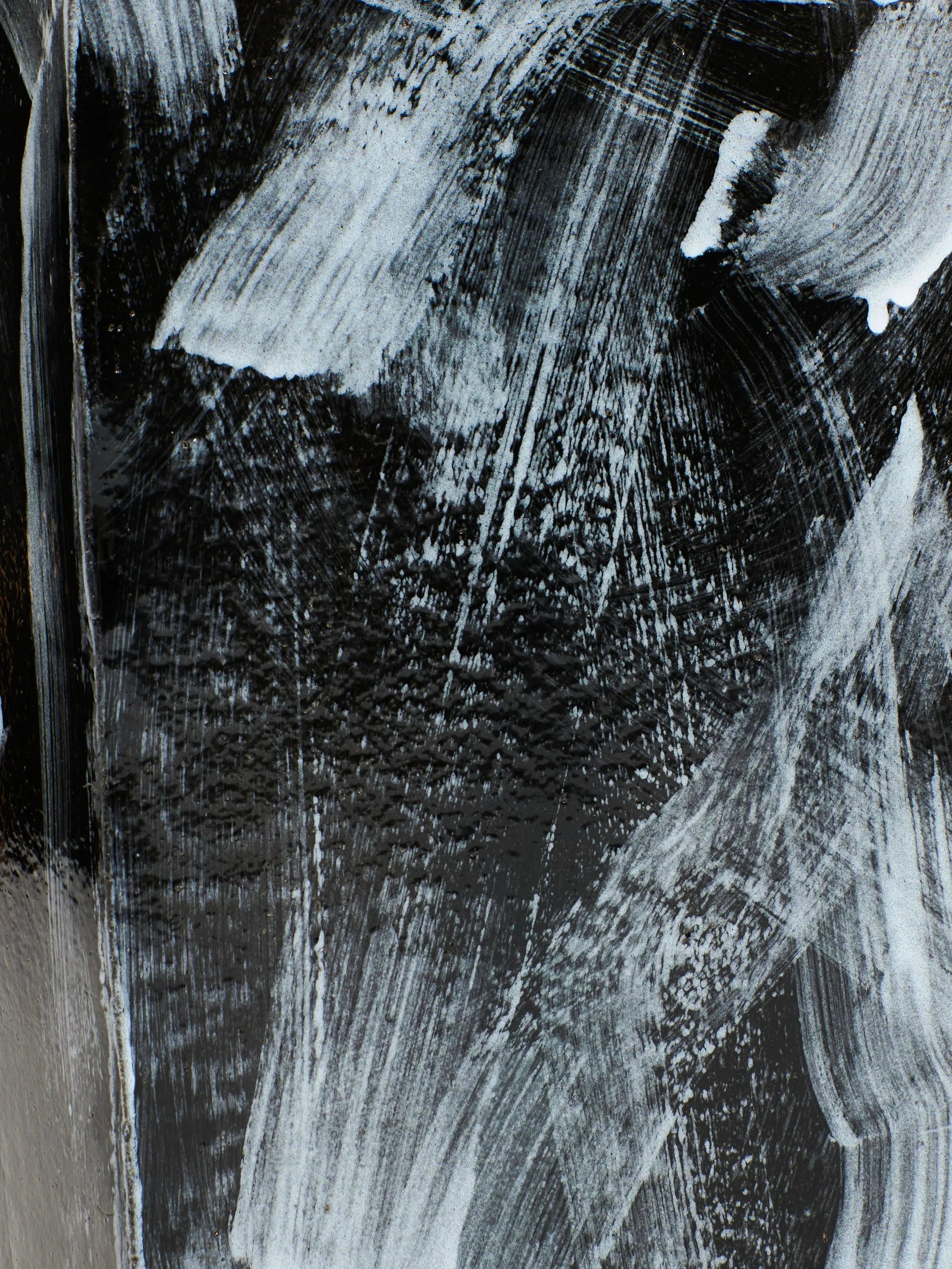 An abstract painting showcasing bold, dynamic brushstrokes of white paint on a dark, likely black background, where the strokes intersect and overlap to form a textured and expressive composition with hints of chaos. This piece is beautifully complemented by the Ceramic Side Table with a Geometric Shape from Project 213A, handmade in Portugal.