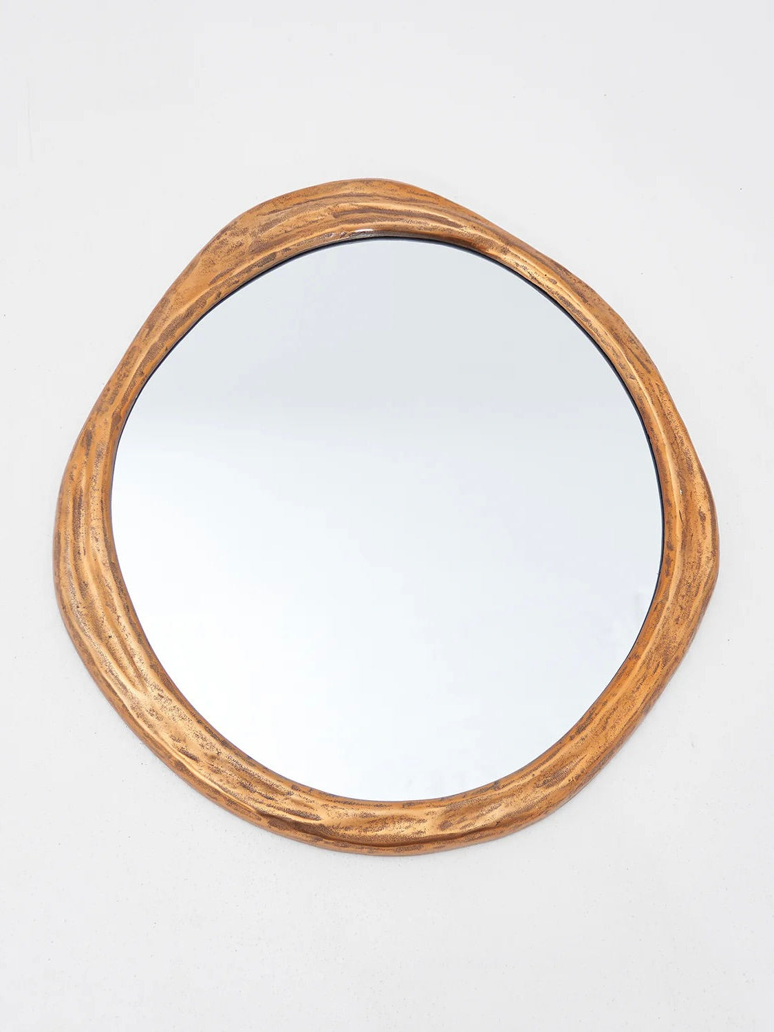 The Rizzo Mirror by LMNOH showcases a round design with a rustic, uneven wooden frame that mimics natural tree bark, seamlessly integrating into modern aesthetics against a plain white backdrop.