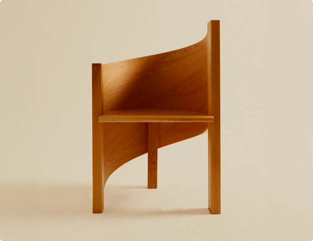 Unique wooden chair with a curved backrest and minimalist design, showcasing clean lines and natural wood texture.