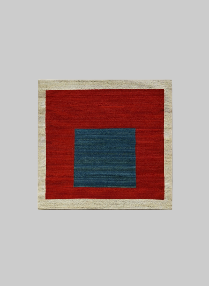 The ISHKAR Squares Kilim Pomegranate - Handwoven Rug featuring a bold design. Handwoven from wool and colored with natural dyes, it boasts a wide beige border, a large red field in the middle, and a smaller, centered blue rectangle. The contrasting colors create a striking geometric pattern.