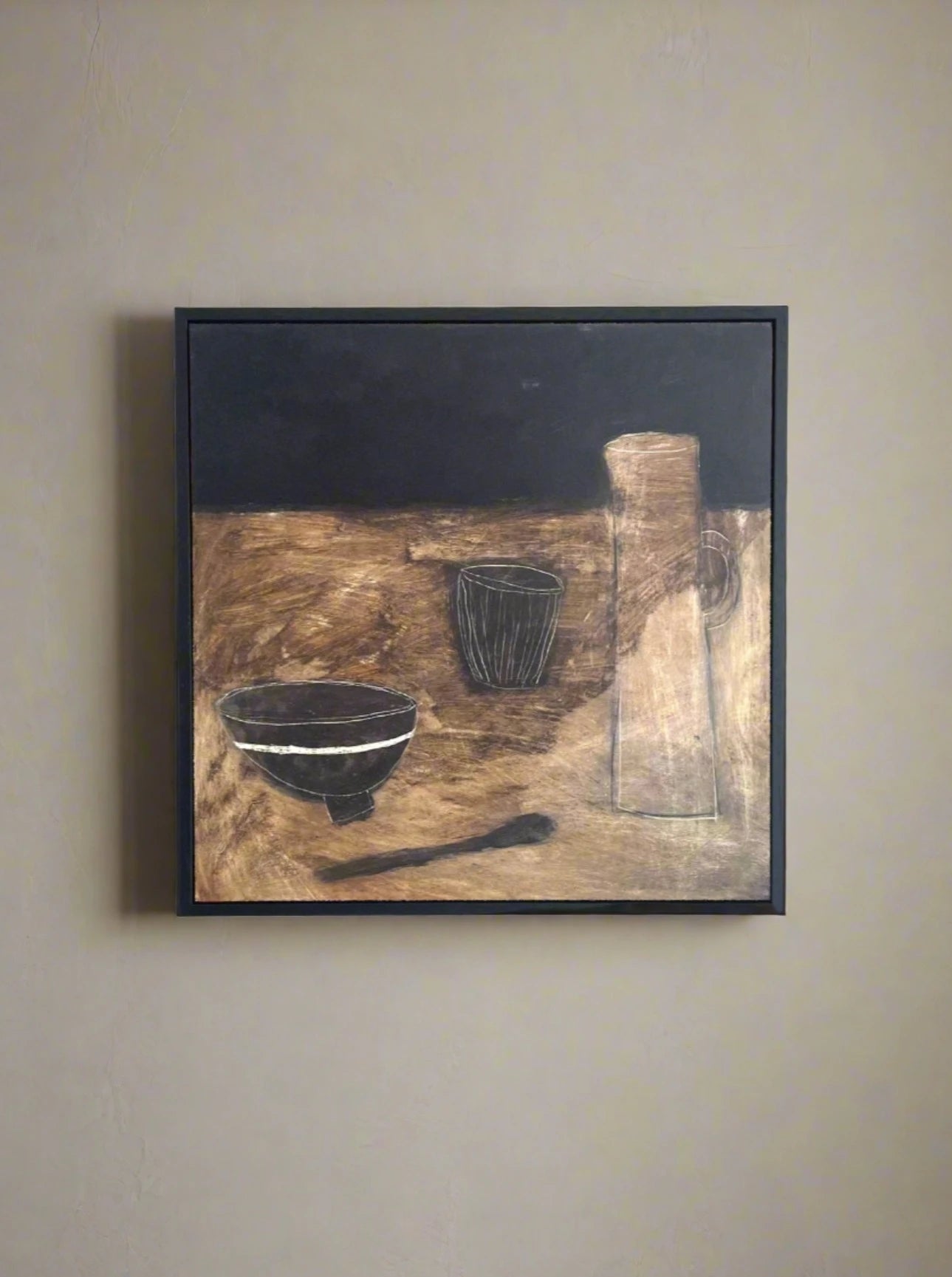 A modern original painting depicting a pitcher, a cup, and a Little Black Bowl on a textured table, predominantly in shades of brown, black, and gray, framed on a white wall by Lara Voce.