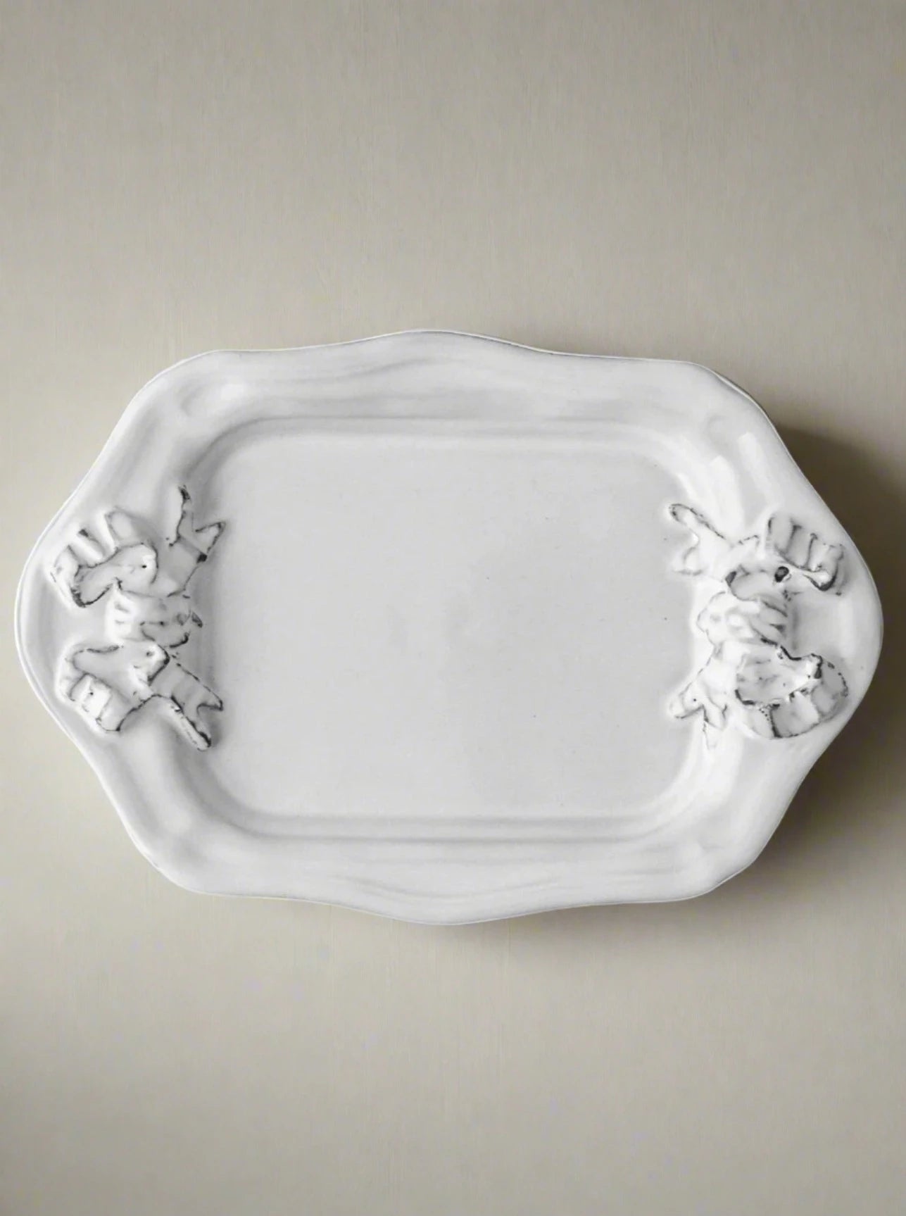 A white enameled terracotta clay Marie-Antoinette Ribbon Rectangular Platter with decorative handles shaped like frogs, displayed against a plain white background. (Brand: Carron)