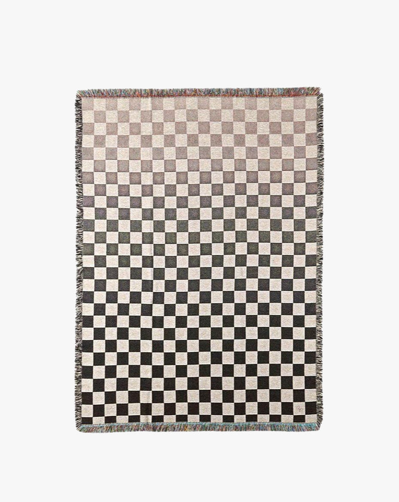 A rectangular area rug featuring a checkerboard pattern in muted shades of brown, gray, and cream, with a textured jacquard woven cotton fringe on the edges.
