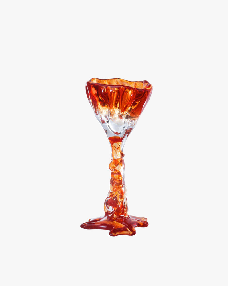 A translucent orange Spiky Cocktail Glass - Red #1 hand-blown by Szkło Studio with a twisted stem and a wide, fluted bowl, standing against a plain white background.
