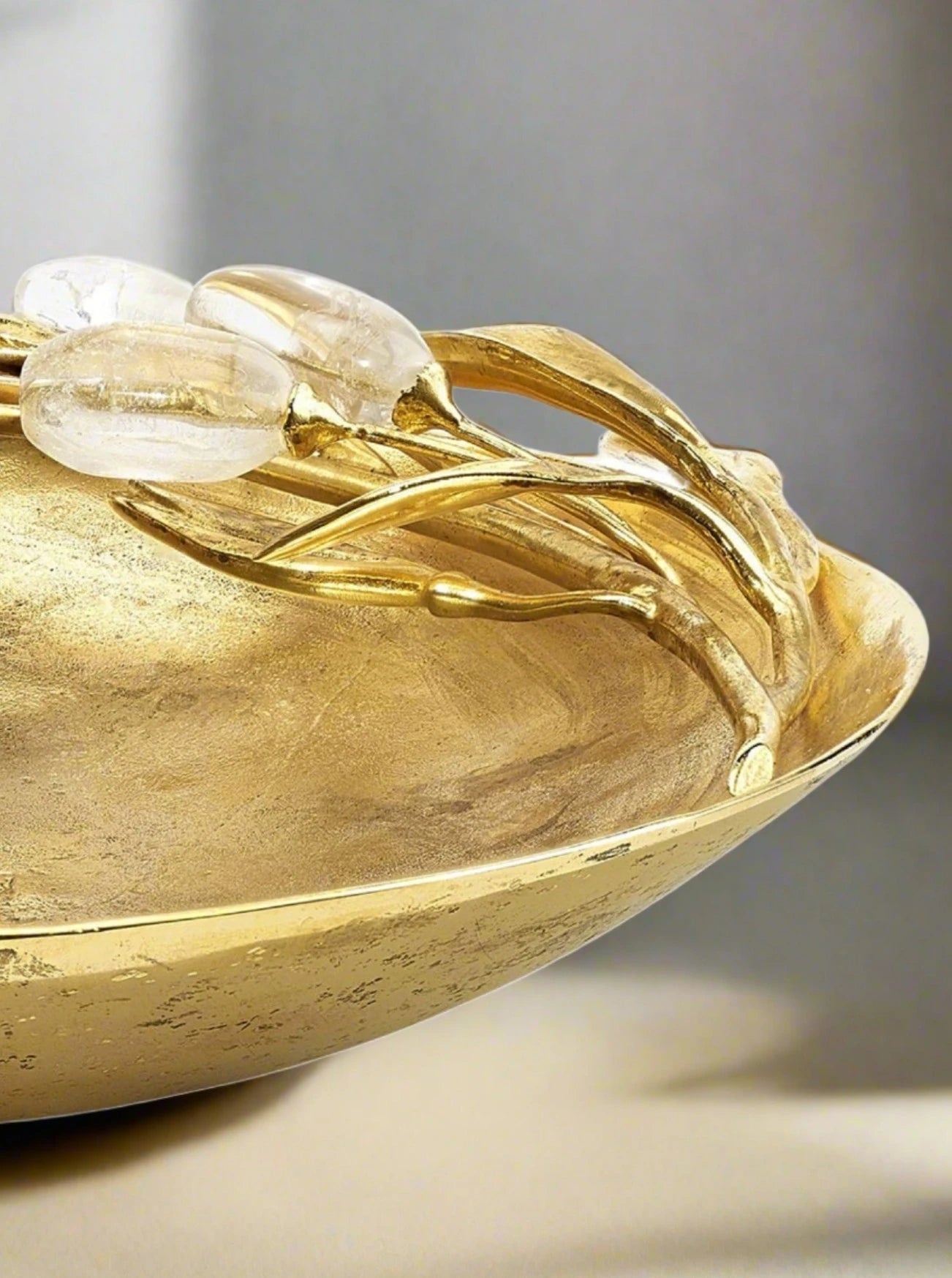 Close-up of a luxury Foliage Trinket Bowl by Goossens Paris with embossed floral designs and inlaid translucent gemstones.