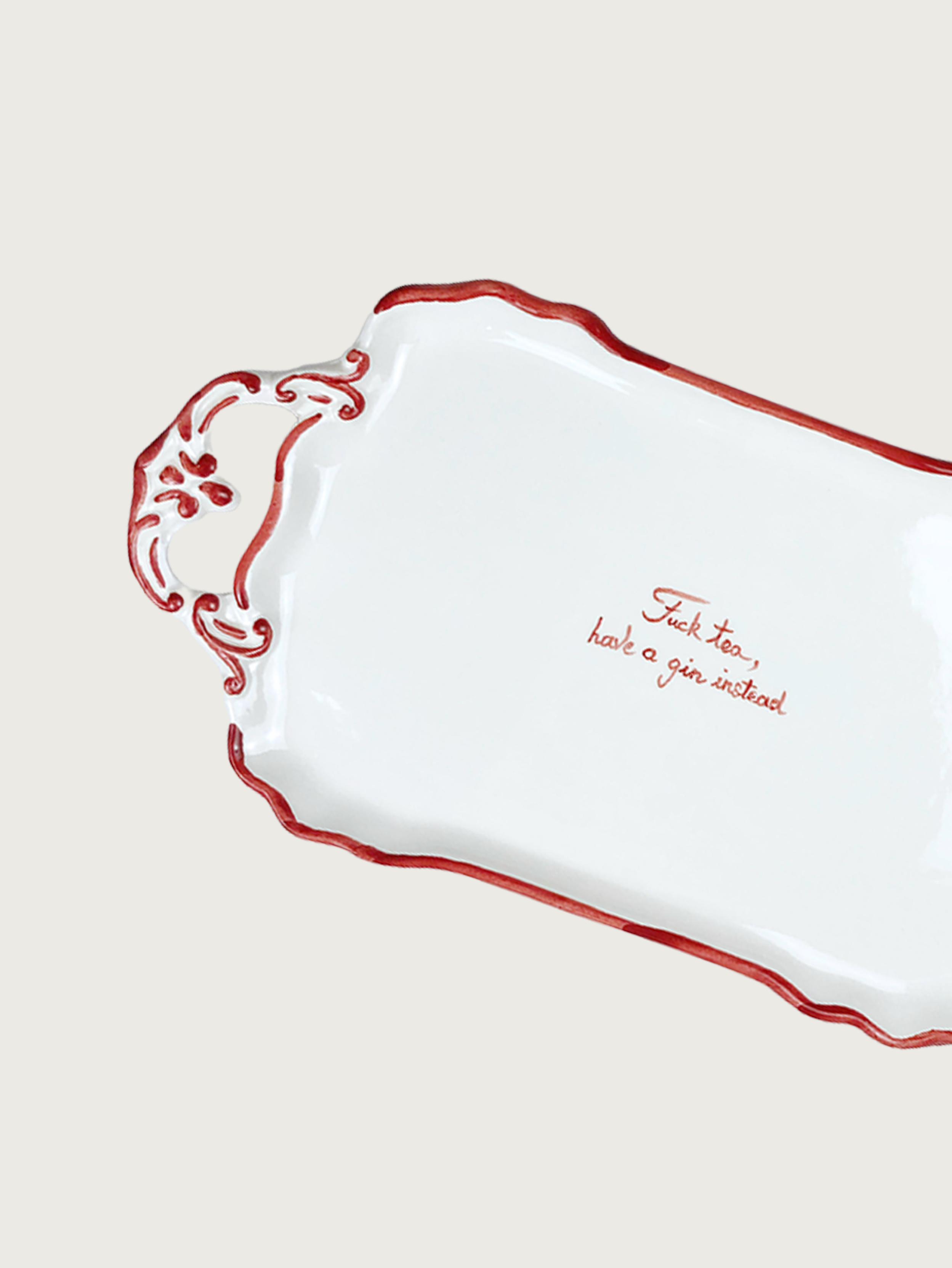 The "F*ck Tea" Tray by Musae Studio is a white ceramic tray with ornate handles, vibrant red edges, and a cheeky cursive inscription: "Fuck tea, have a gin instead." Perfect for gin lovers!.