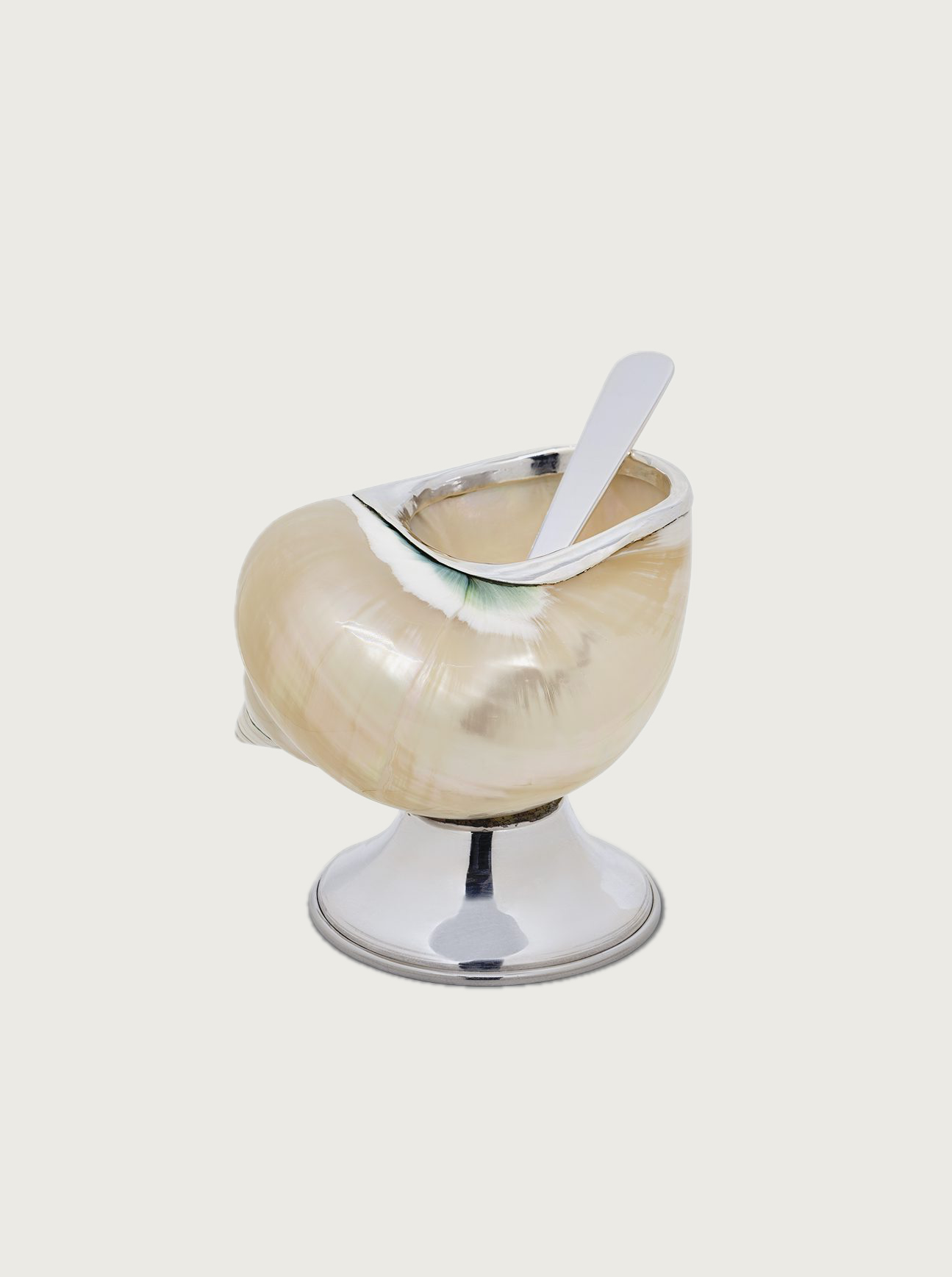 A unique dessert dish shaped like an onion, made of iridescent glass on a metal pedestal, containing a white dessert with a silver spoon is the Shell Sugar Bowl from Tavares 1922.