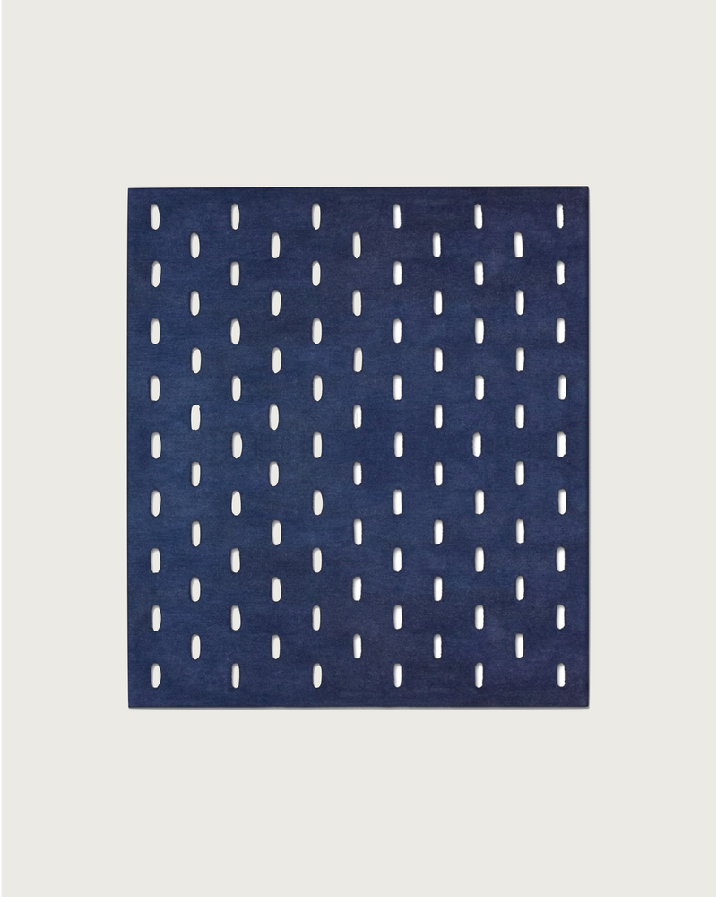 The GRATA BLU rug by Hafner Büro features a square marine blue design with vertical oval cutouts in a grid pattern on a light background.