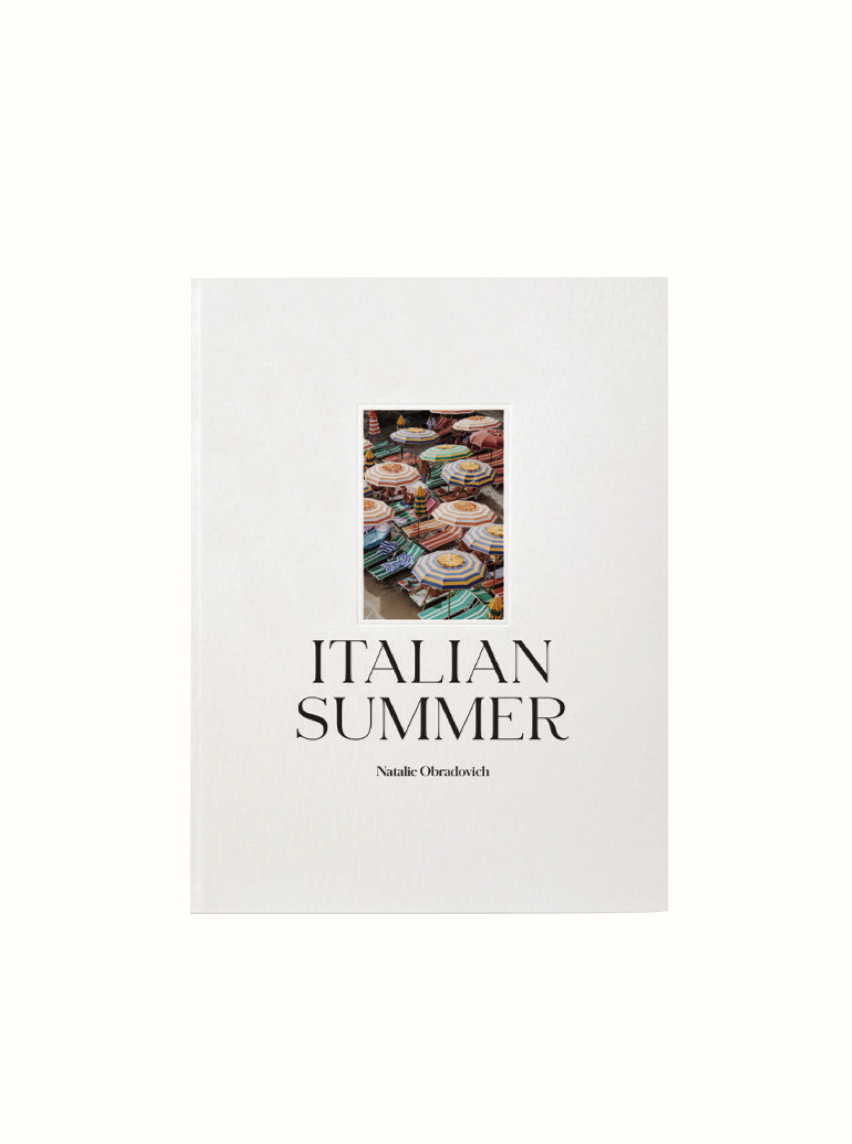 The cover of the Italian Summer Book by Natalie Obradovich, a product from Maison Plage, features a central photo of colorful plates displayed in a market setting. The title and author's name are centered below the iconic photo on an otherwise minimalist white background.