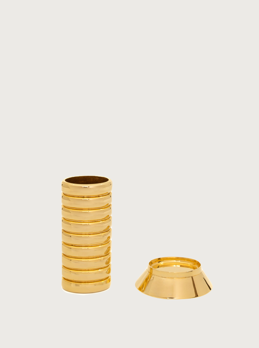 An image showing two pieces of a gold-colored object. The left piece is a cylindrical tube with horizontal grooves, and the right piece is a conical base. This stylish lighter accessory, known as the Gio Lighter Holder by FRY POWERS, rests against a plain, light-colored background.