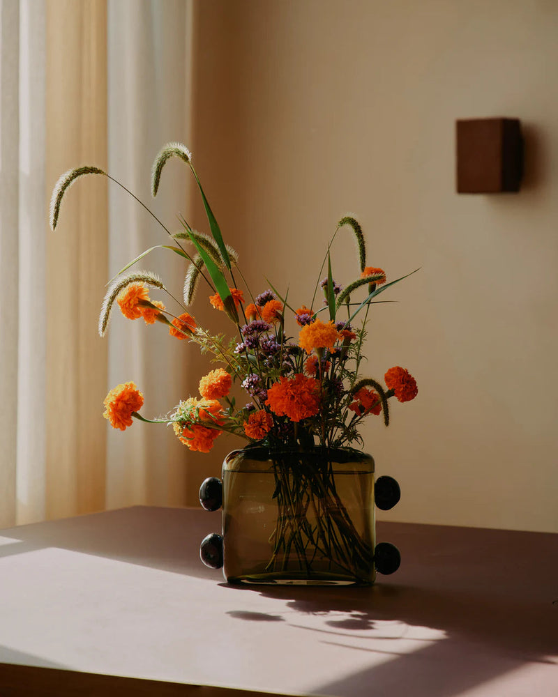 Amber glass La Pierre vase with black dots holding wildflowers