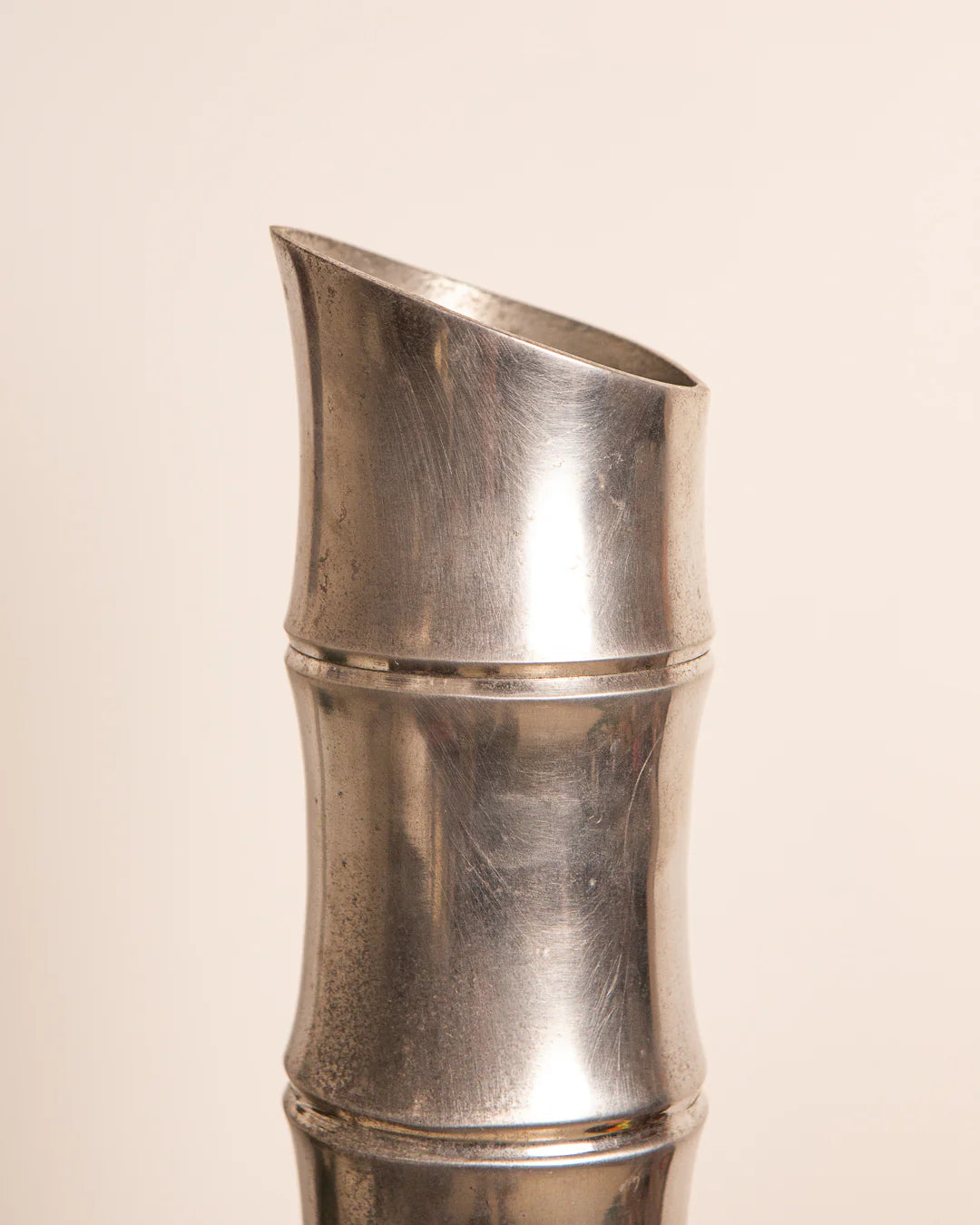A stylish Treaptyque Large Cast Aluminium Vase ‘Bambou’ from the 80s, featuring a silver color with a smooth, slightly angled opening and bamboo segment design. The plain off-white backdrop adds a touch of vintage charm.