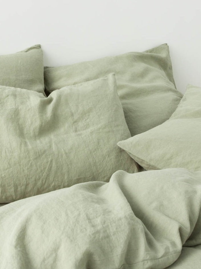 A MOST Washed Linen Bed Set in Sage, casually draped on a bed, conveying a cozy and inviting atmosphere.