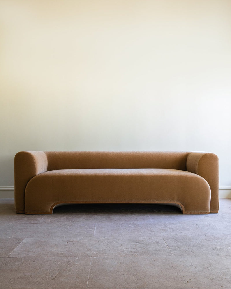 Modern curved Quincy sofa in camel velvet by Studio OSKLO