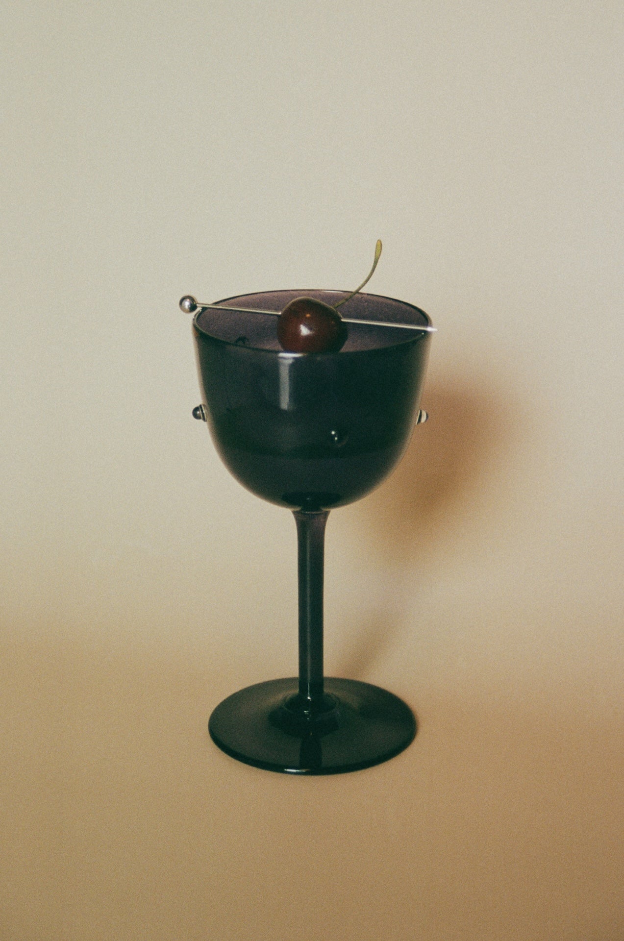 NOA GOBLET cocktail Glass — close-up of black glass with cherry garnish