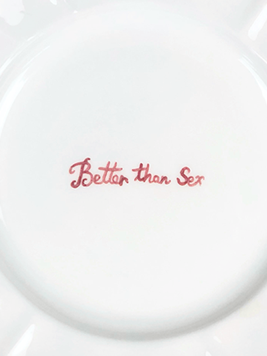 The "Better than Sex" Fil Rouge Plate by Musae Studio is a white plate with hand-painted red cursive text.