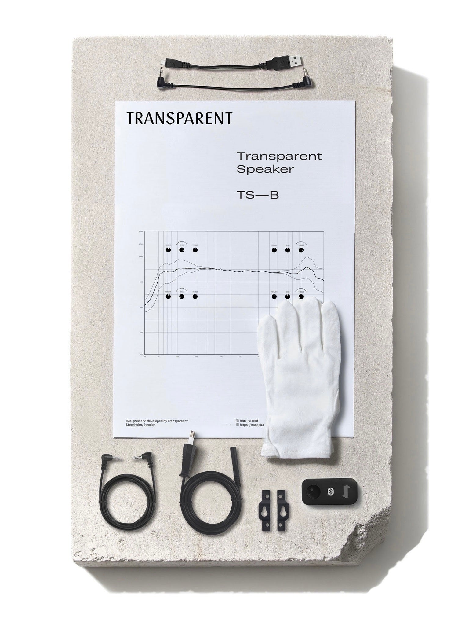 Transparent Speaker Black - Bluetooth — top view with accessories on concrete surface