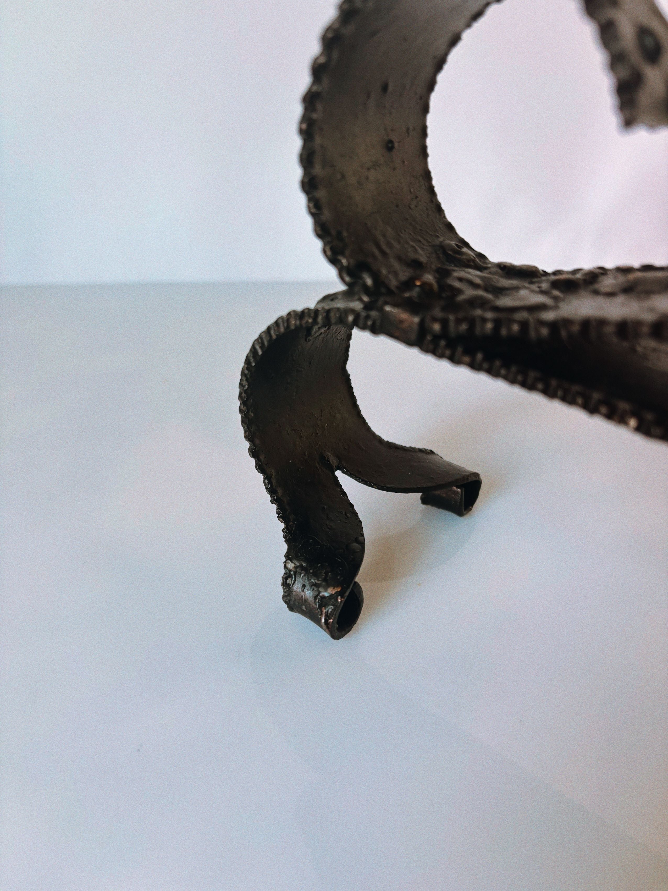 Curved metal candleholder tentacle detail showing textured surface