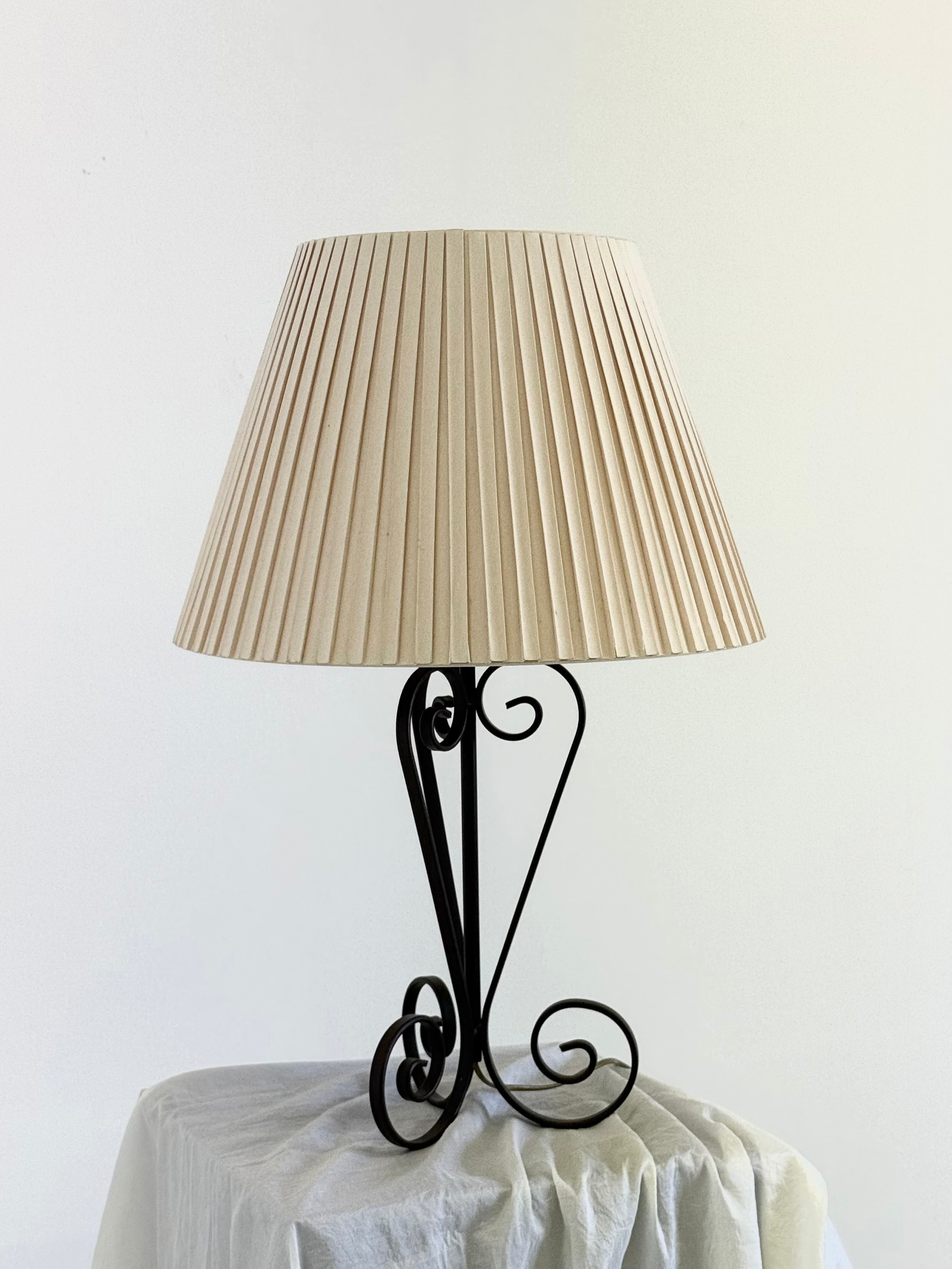 Vintage wrought iron table lamp in a swirl shape with a pleated shade — lifestyle setting