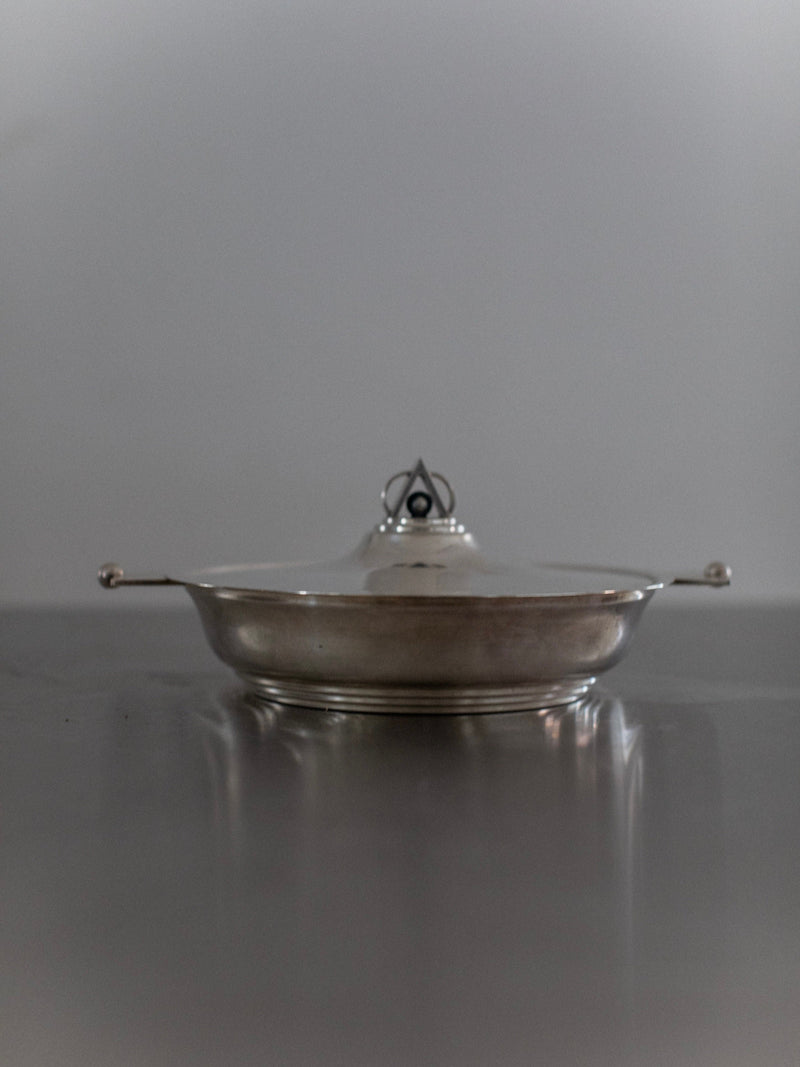Silver Art Deco serving bowl with lid and handles on reflective surface