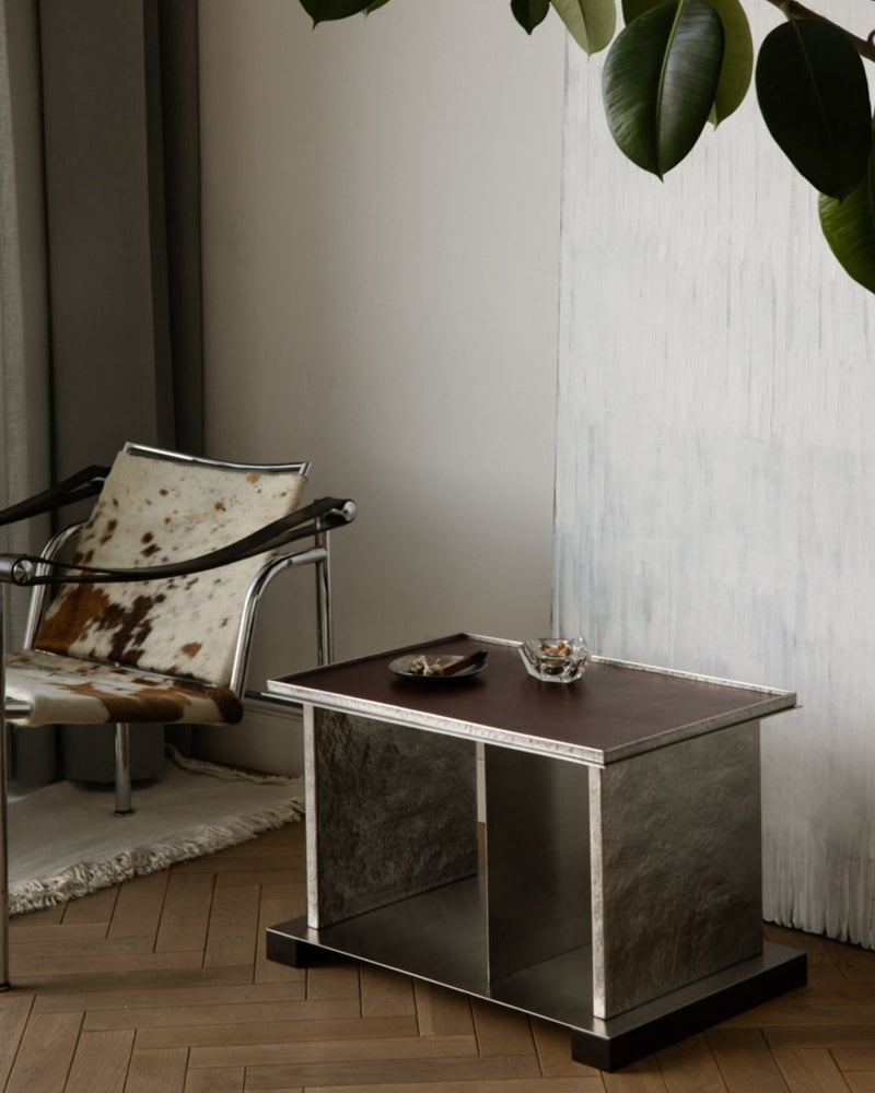 YUMA side table with dark marble base and cowhide chair in modern interior