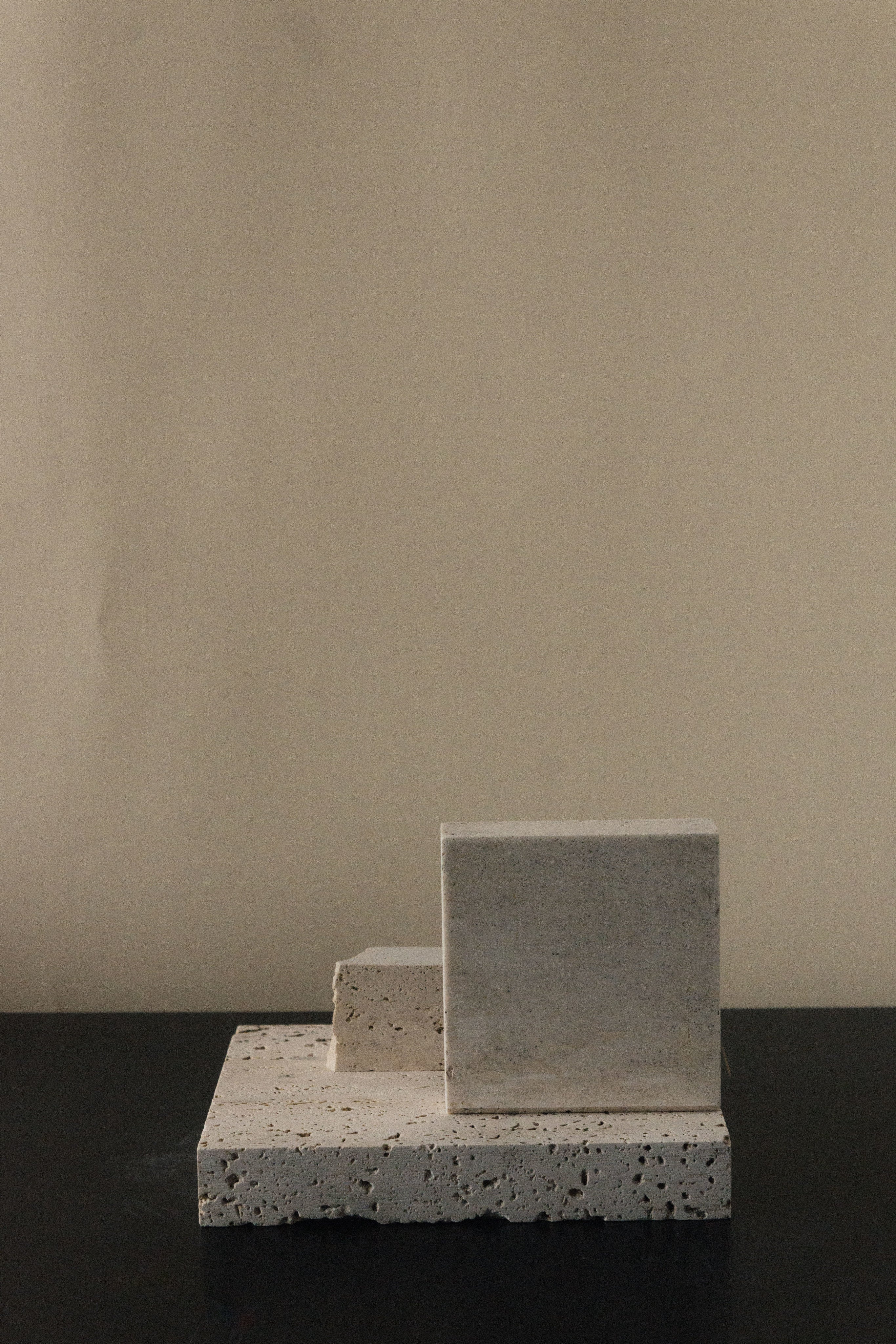 Monument II - Handmade Travertine Marble Bookstand — side angle showing textured surface on dark table
