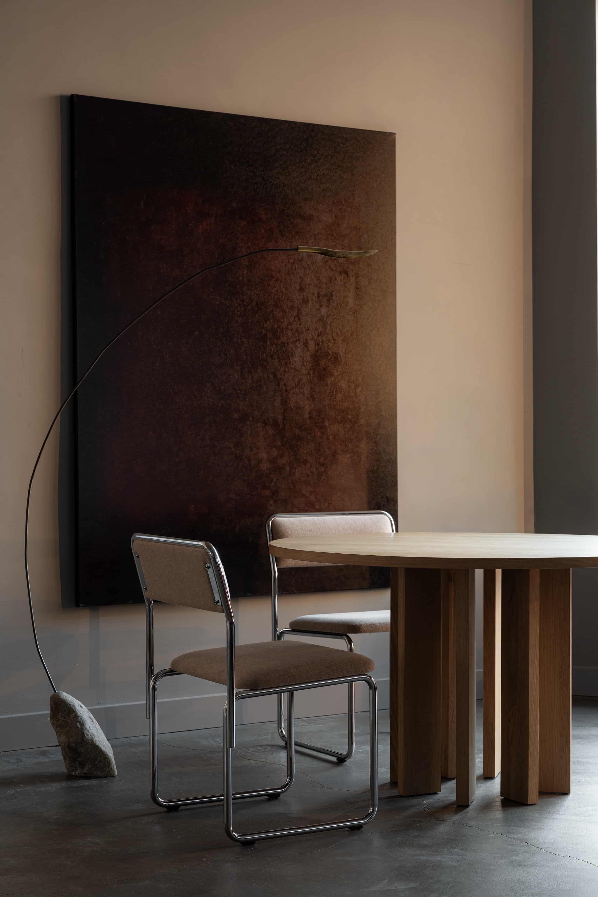 Thola Round Table — side angle with wooden legs in modern setting