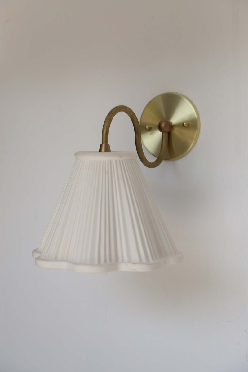 Lucy Sconce — close-up of white pleated shade and brass arm