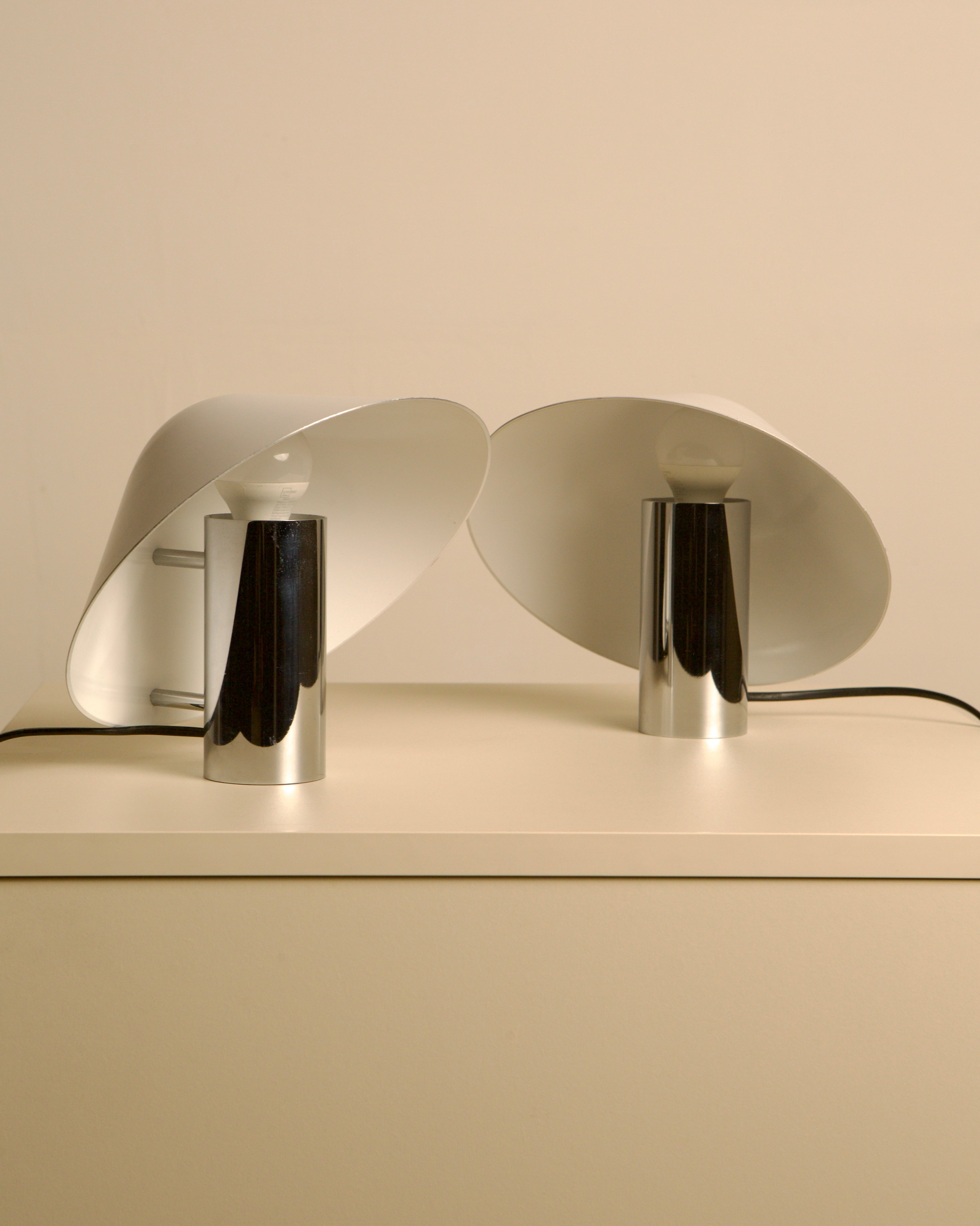 Pair of white Pulcino table lamps with chrome bases on shelf