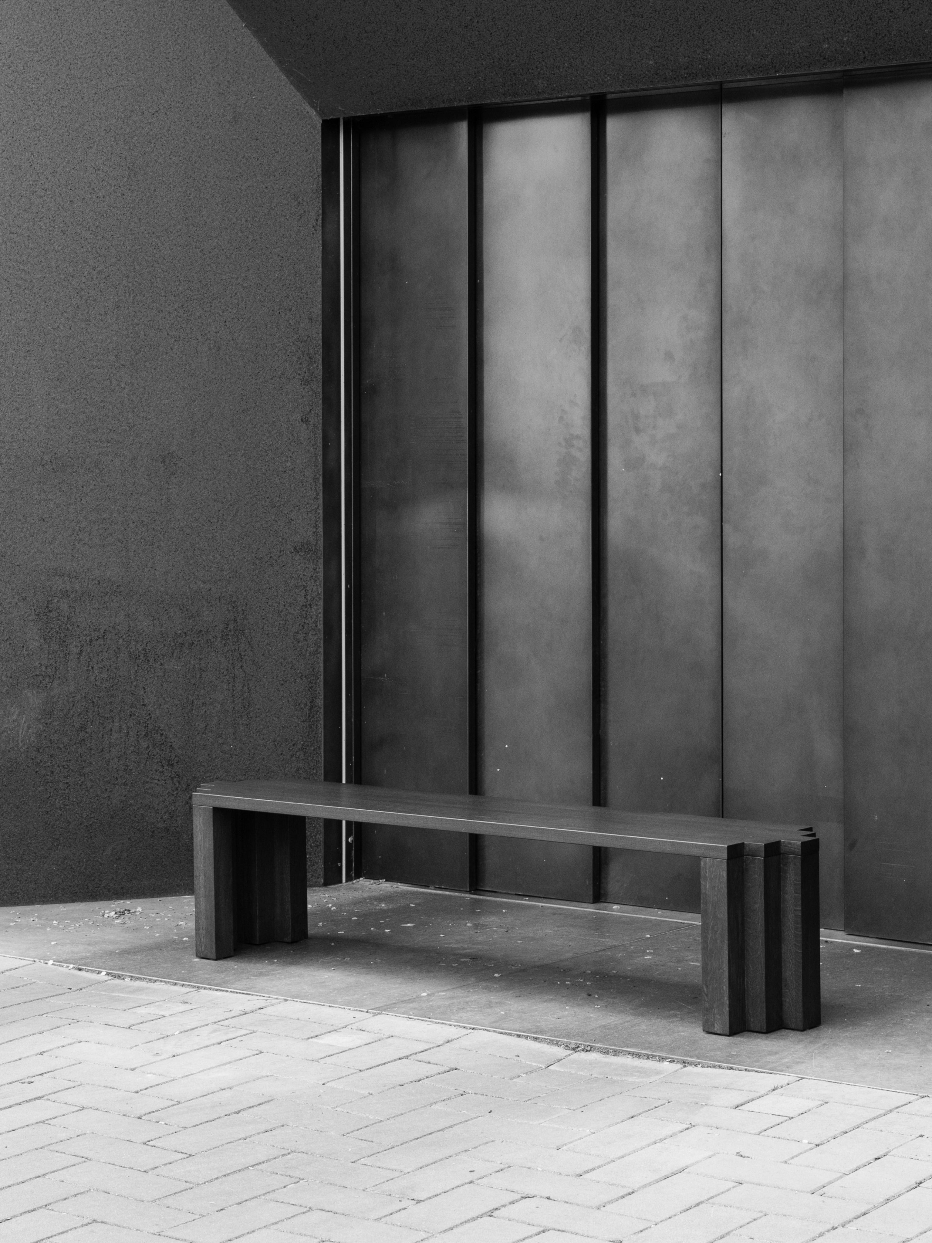 Cadence Bench — black wood bench against industrial backdrop