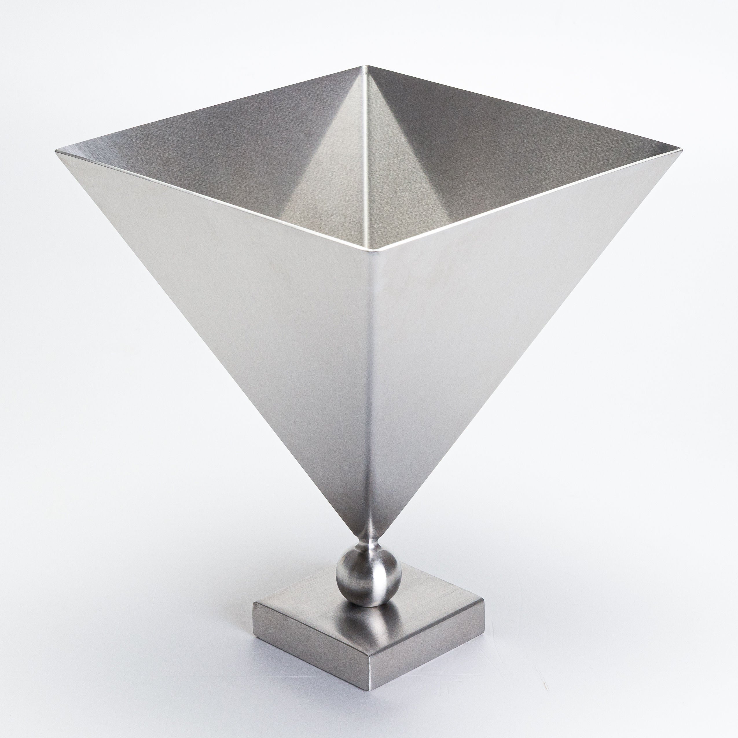 The Stainless Steel 'Vasen' Vase by Studio Vraco features a modern, geometric design with an inverted square pyramid atop a small sphere and square base in brushed silver, set against a plain white background.