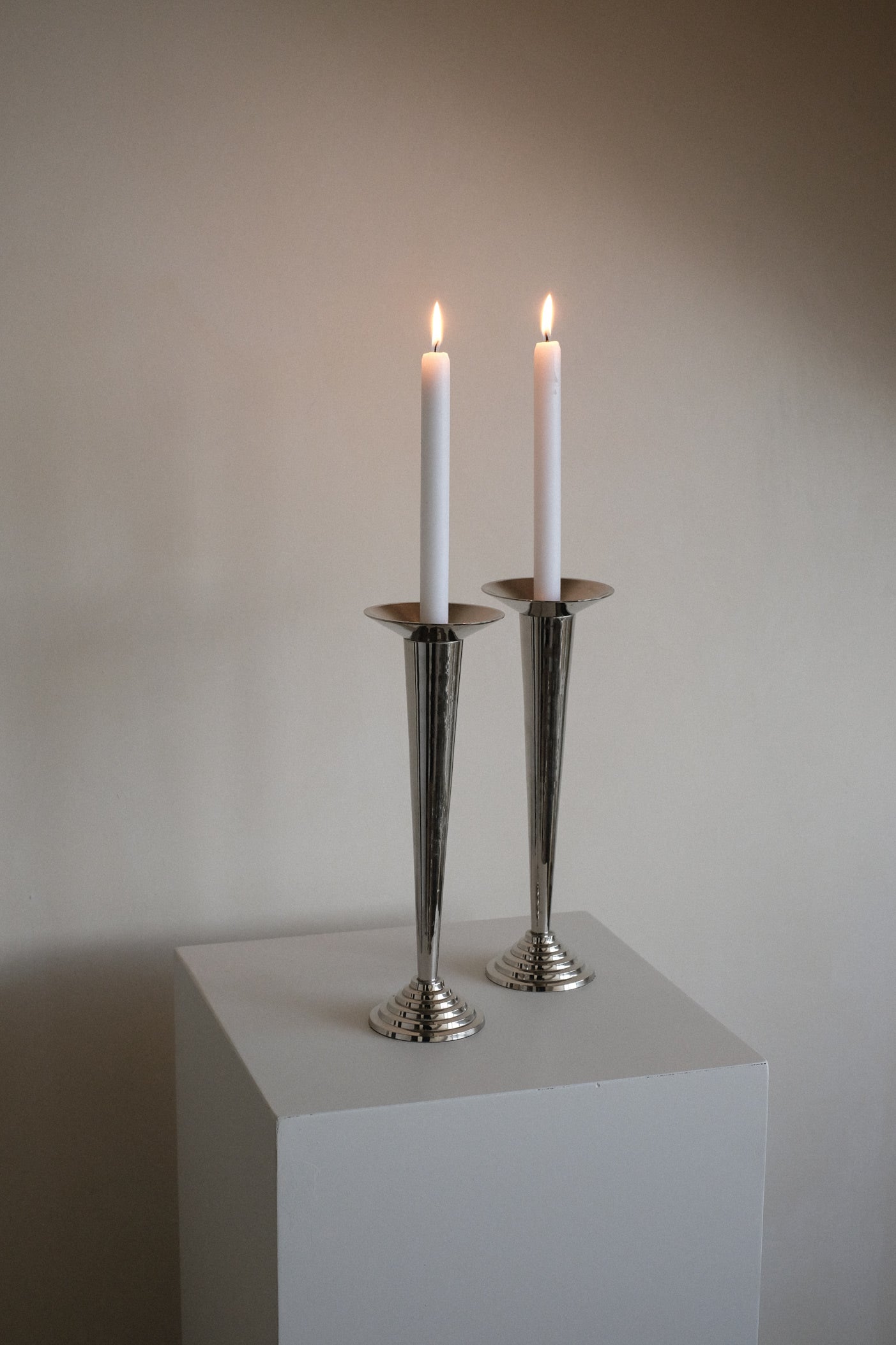 Art Deco Candle Holders — silver holders with lit candles on pedestal
