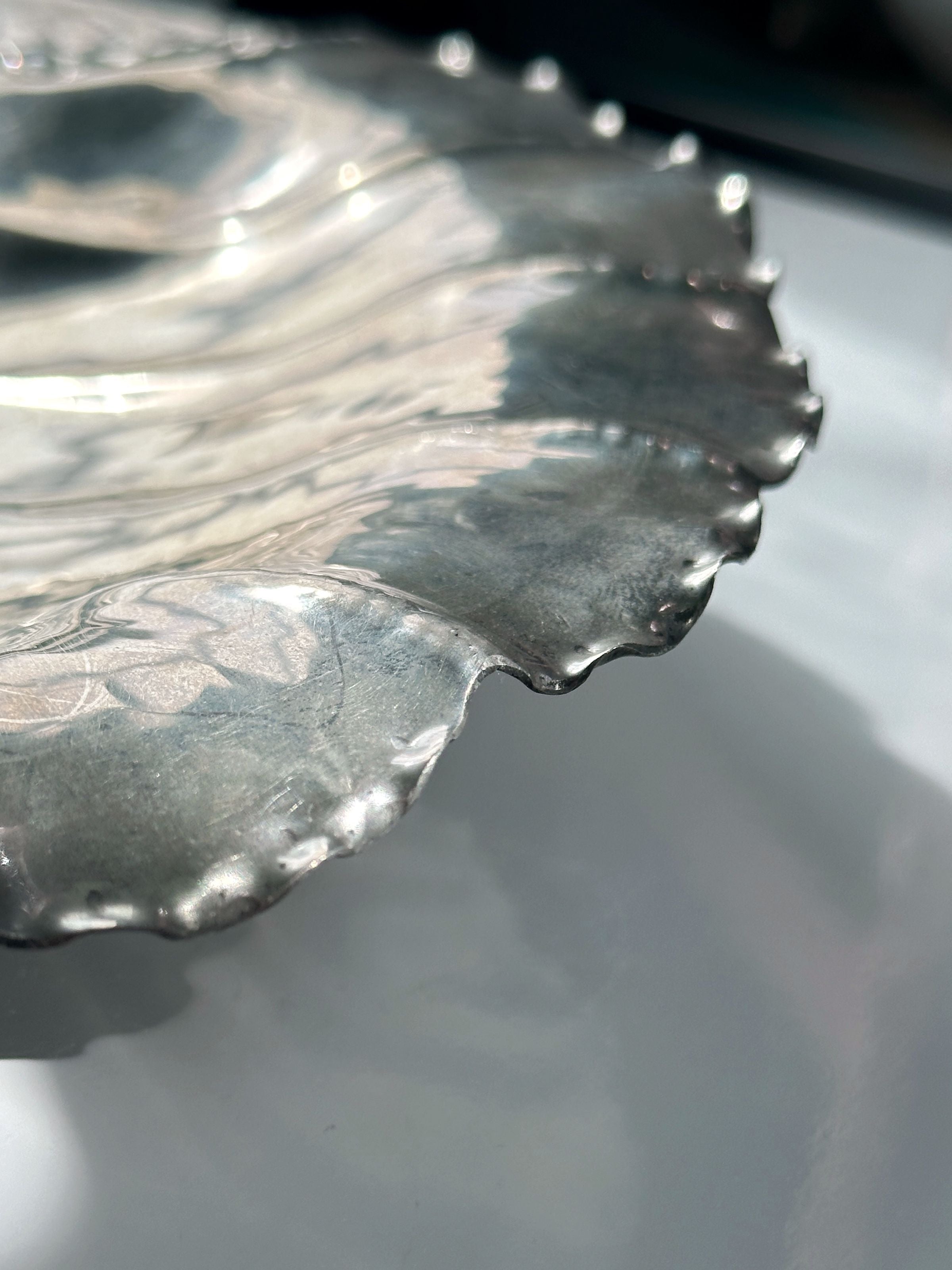 Scalloped edge detail of handmade tin shell bowl