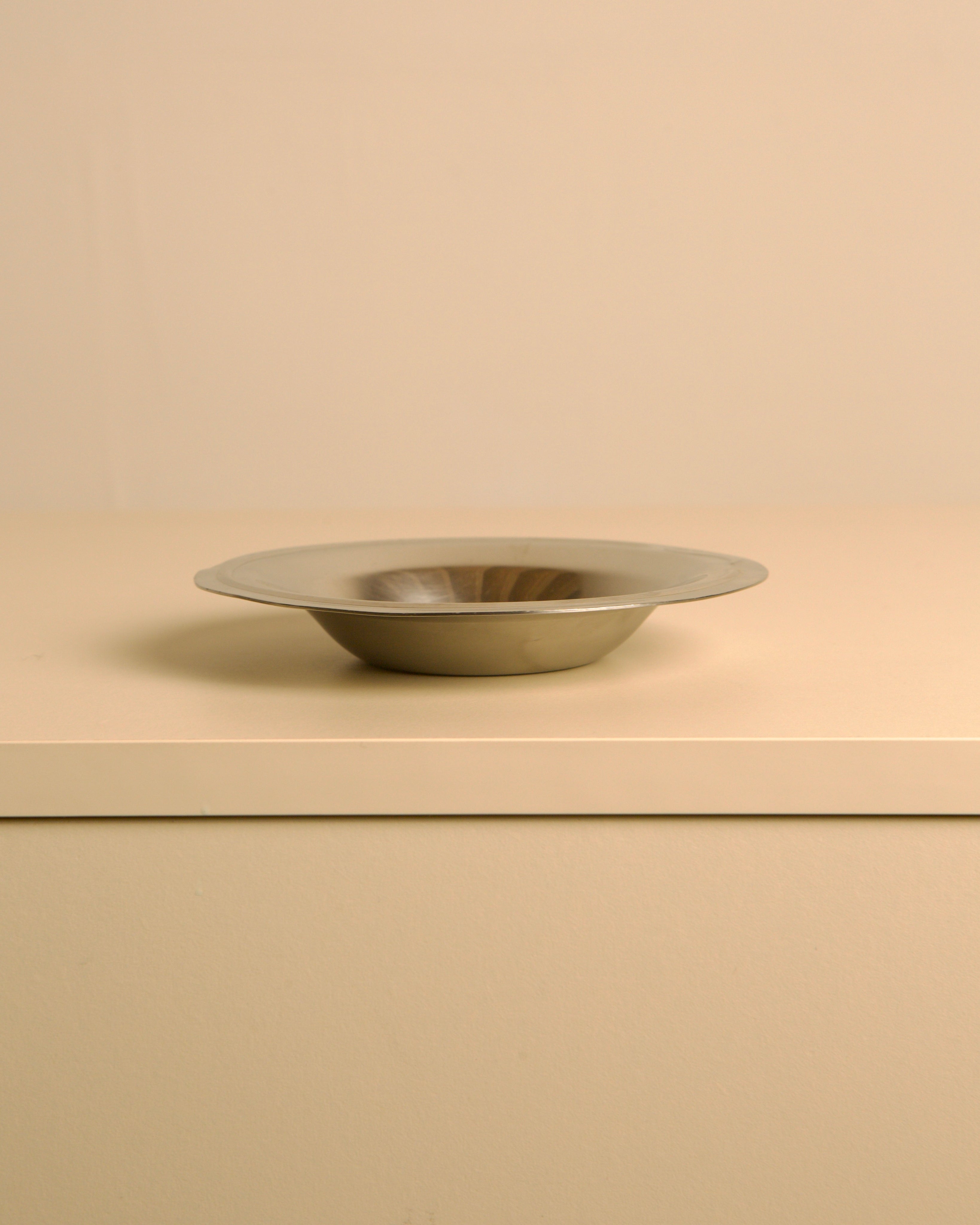 Circular stainless steel valet tray by Pierre Cardin, 1980s — side angle on neutral background