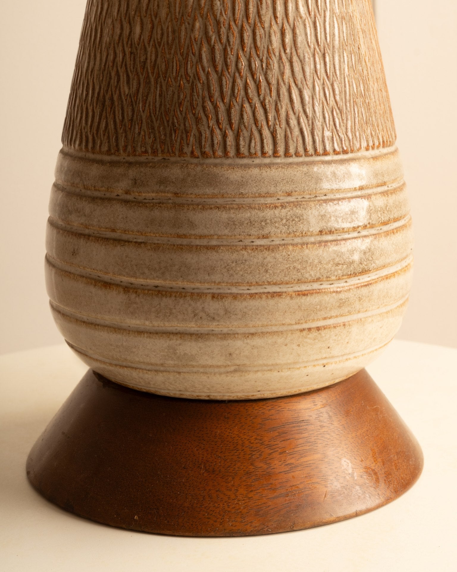 Detail of textured ceramic body and wooden base of Danish table lamp