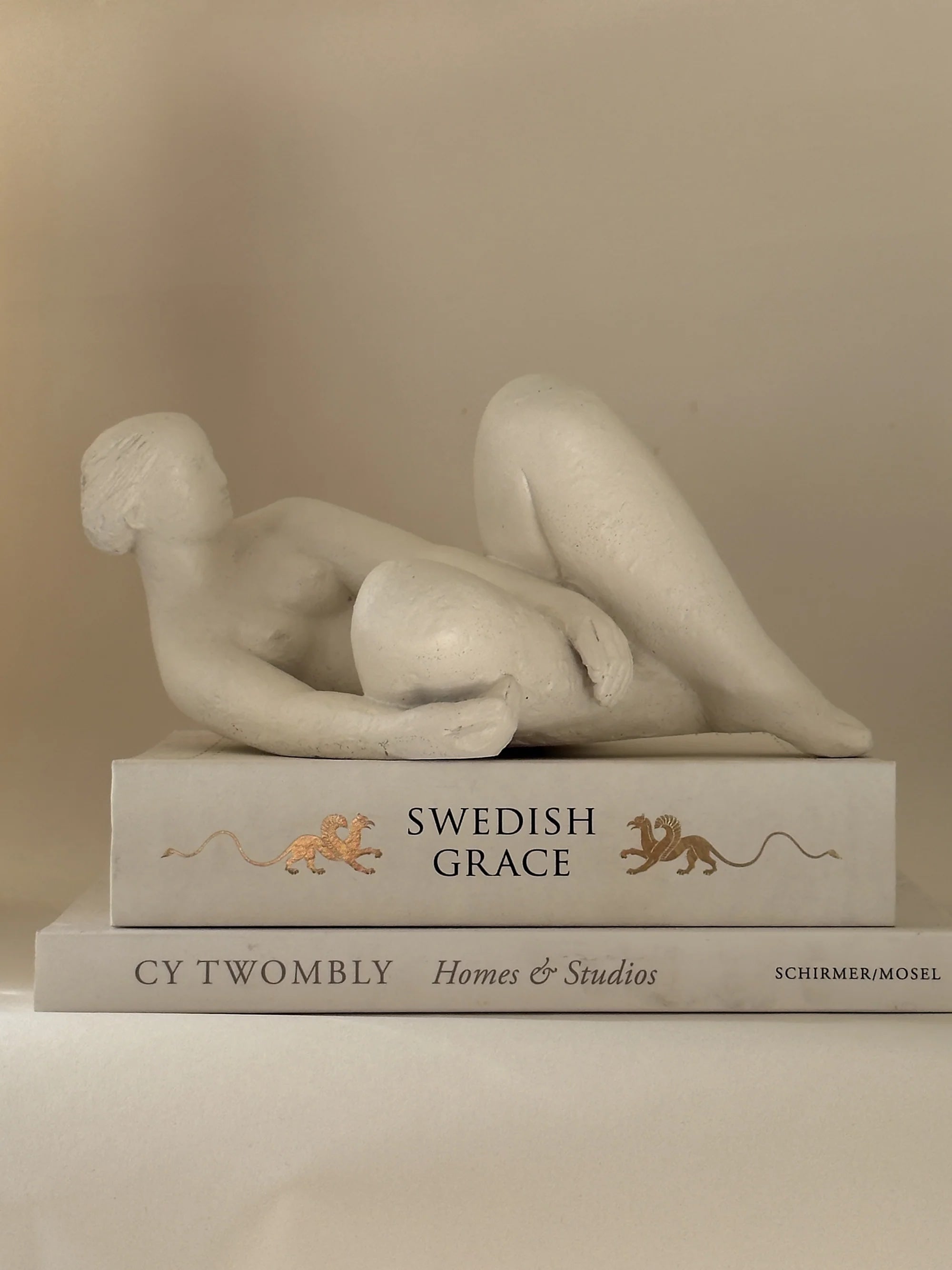 Reclining Female Figure Sculpture, Jan Keustermans — detail on stacked art books