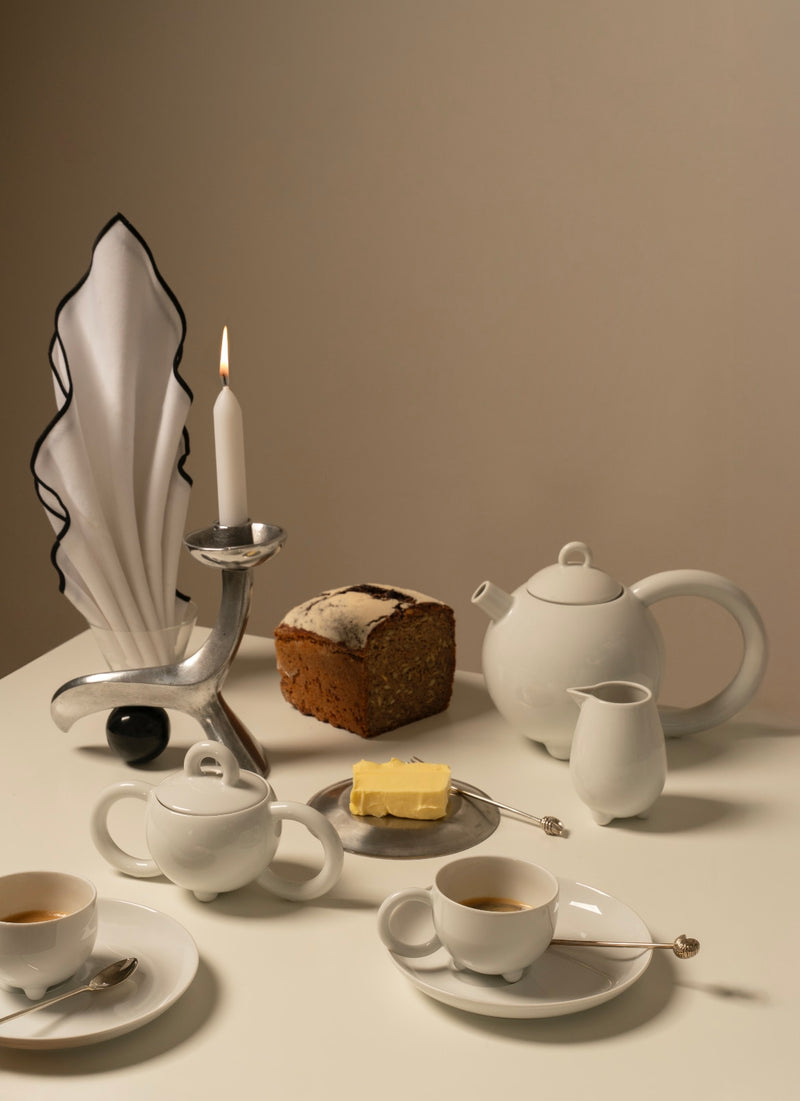 The Linea Candleholder — close-up of polished metal with candle