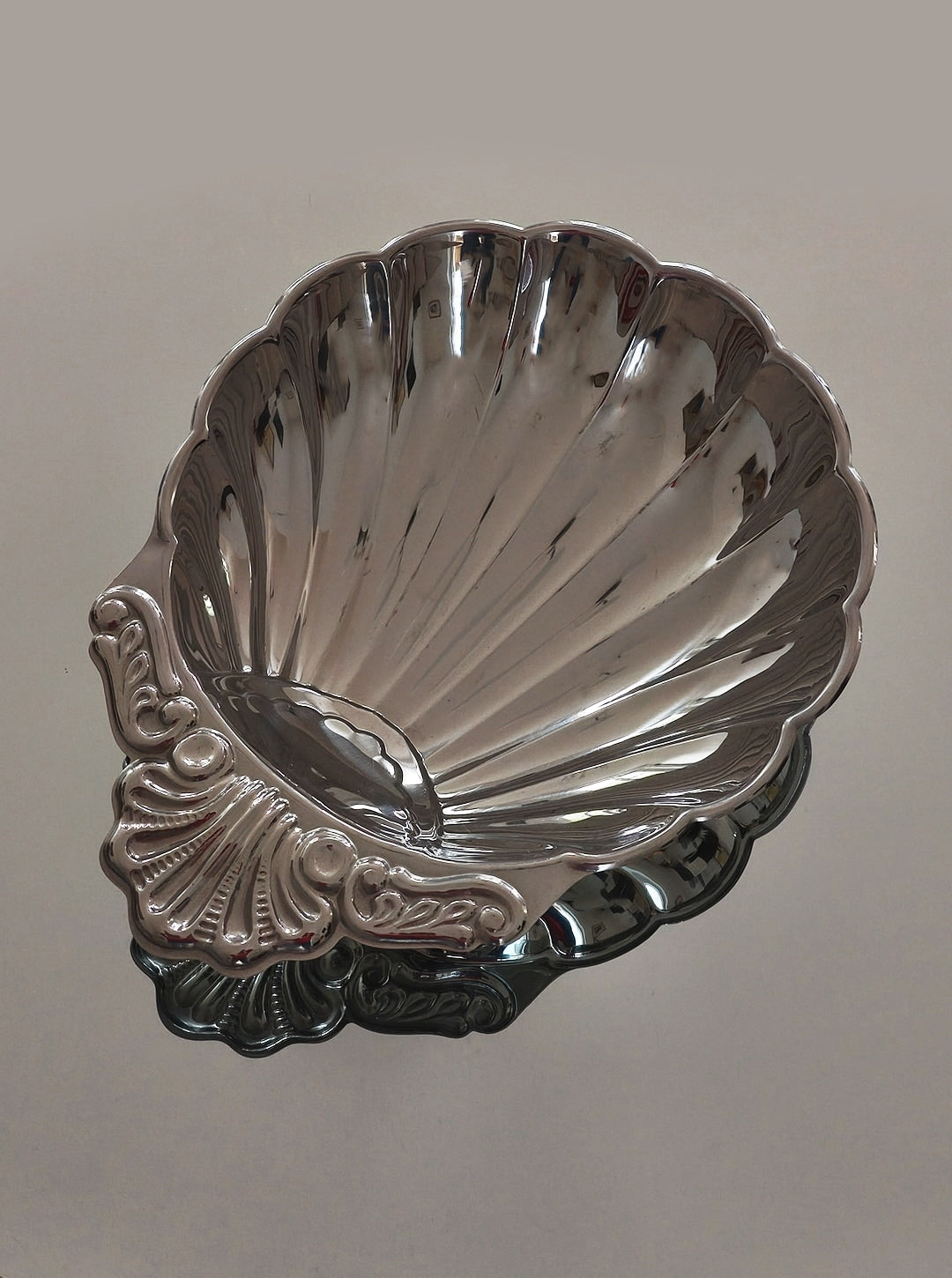 Large steel shell-shaped decorative dish with ornate handle detail