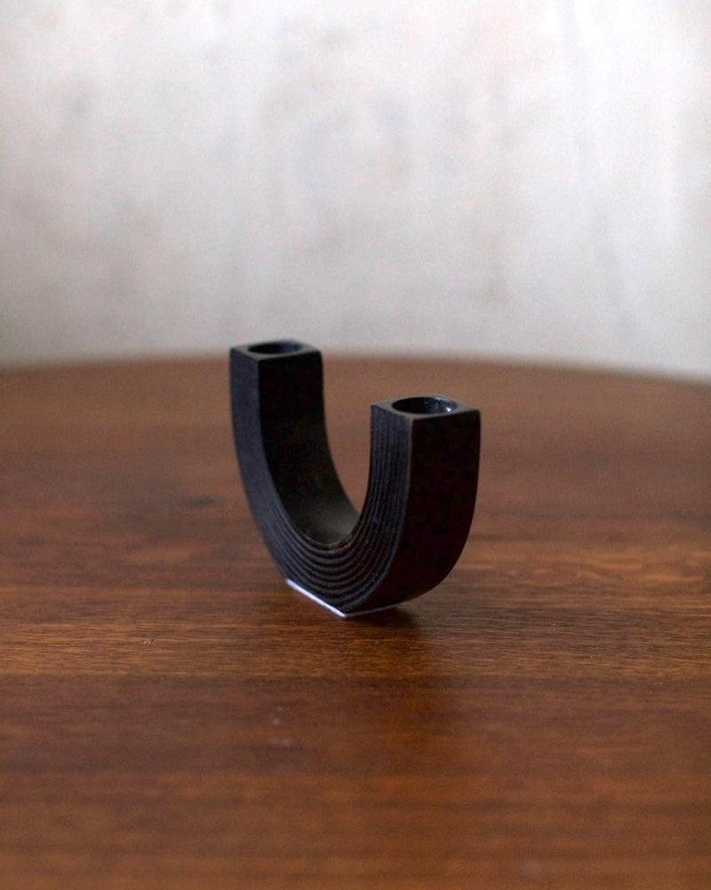 Black Steel Candleholder — close-up showing curved design on wooden table