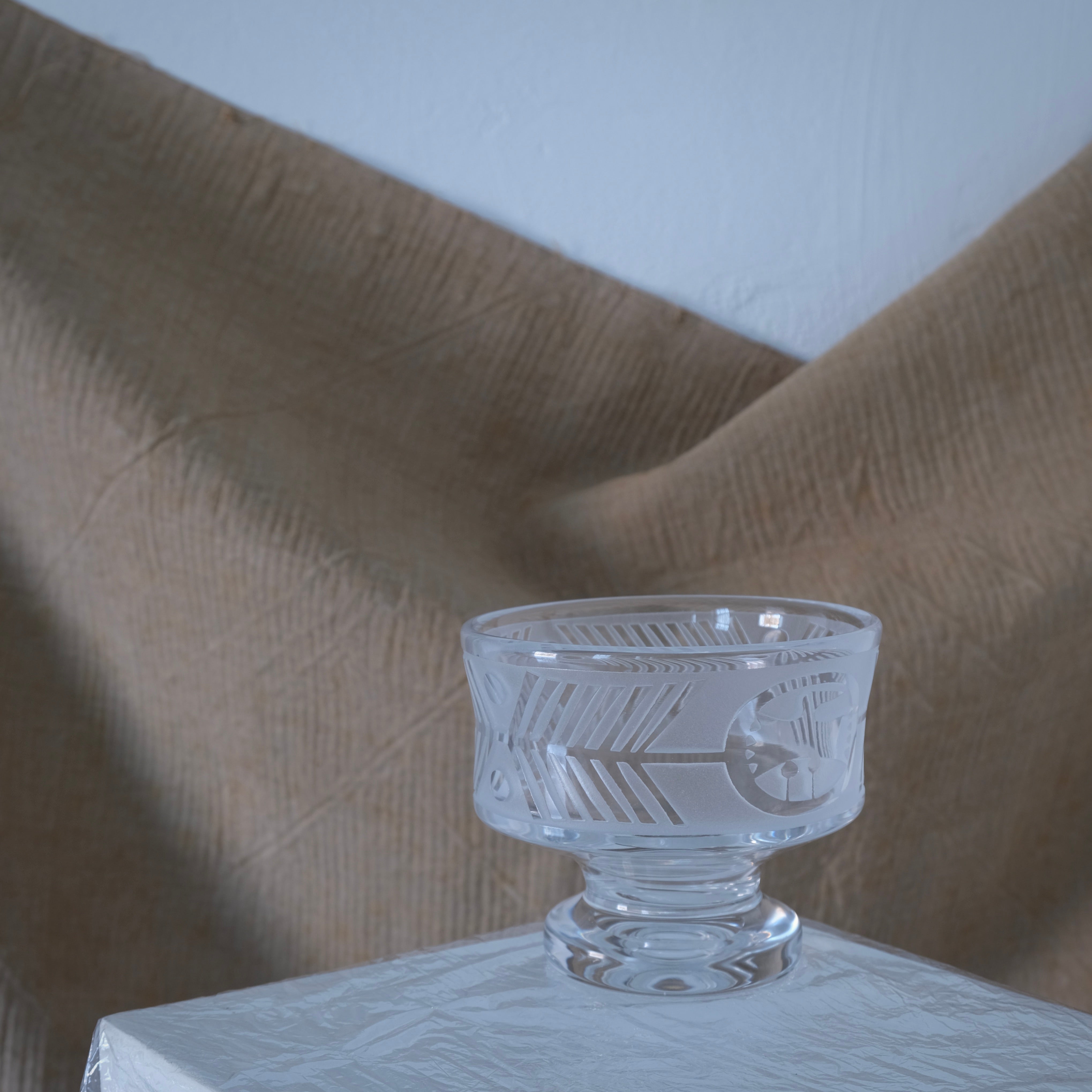 Bertil Vallien Glass Footed Bowl for Boda Åfors, 1960s — displayed on white table against textured backdrop