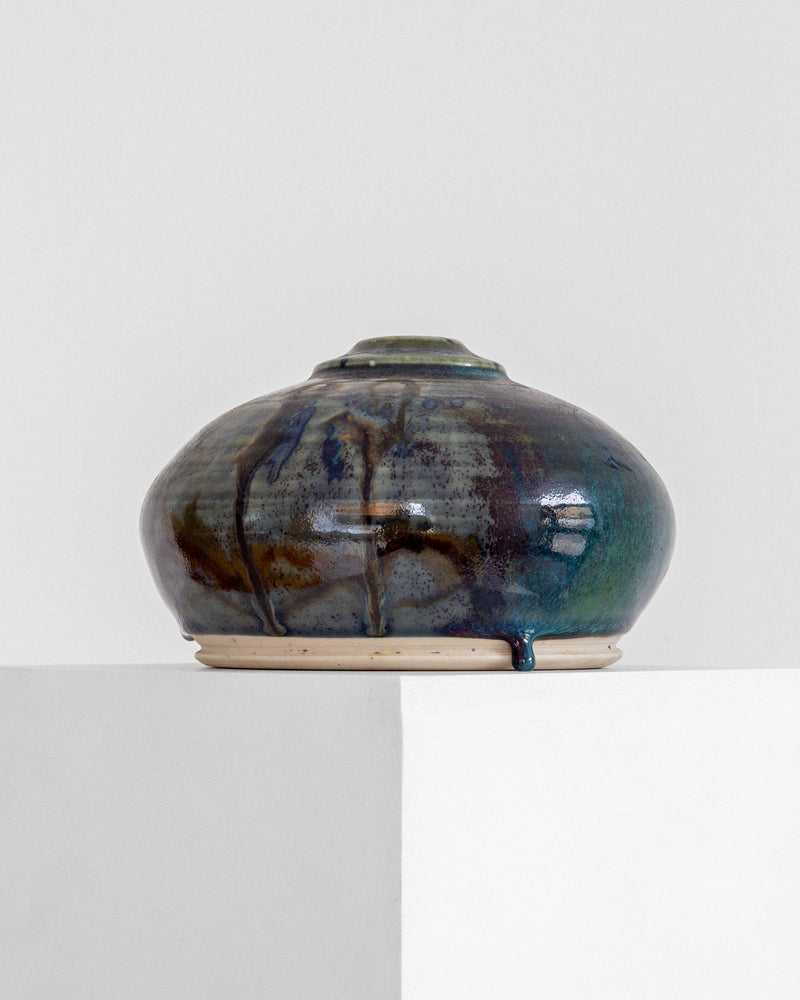Studio pottery vase profile view showing iridescent drip glaze