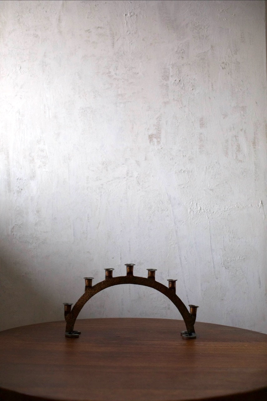 Bronze Candleholder — side angle on wooden table against textured wall