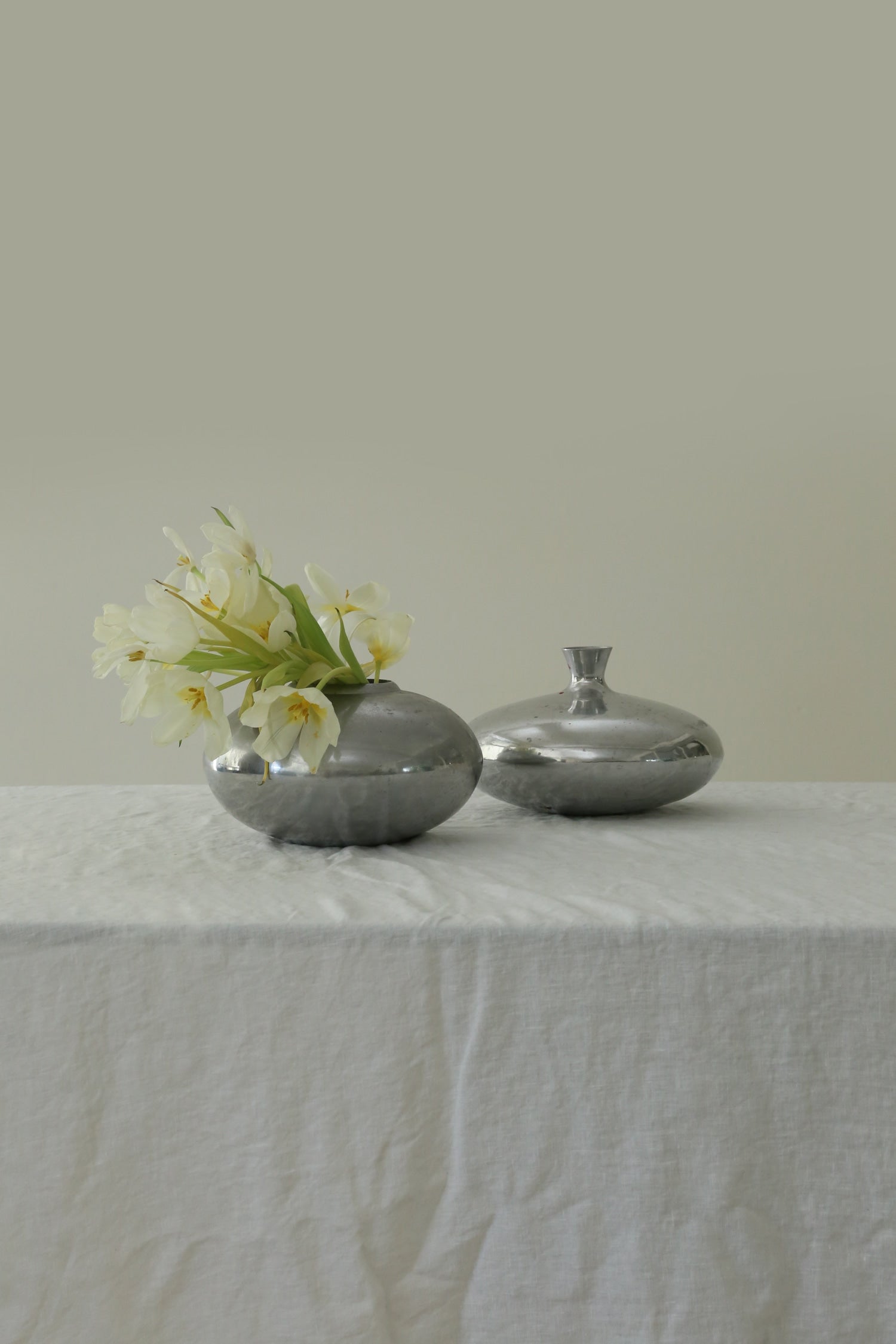 Form Sculpture Vase — close-up of polished silver surface with flowers
