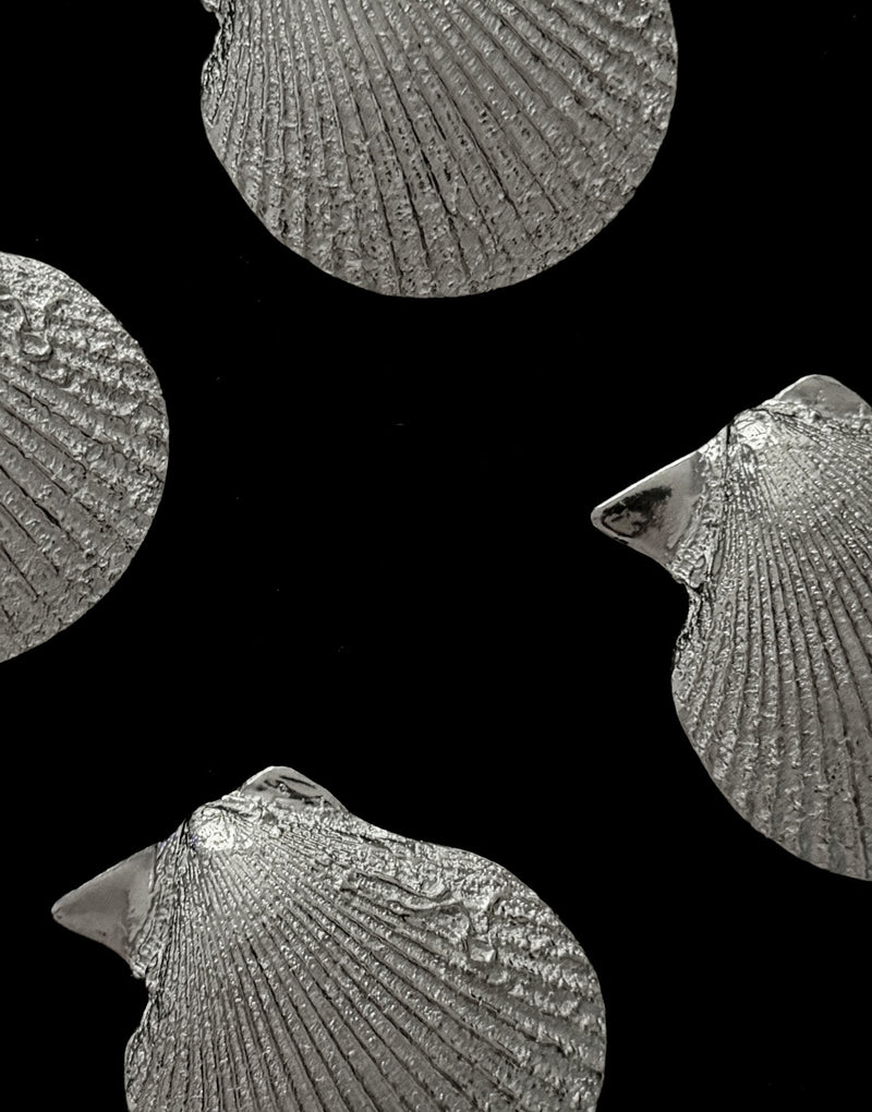 Vintage vide-poches crafted in the form of scallop shells — close-up of textured silver surface