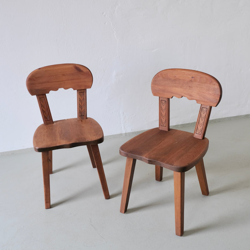 Two rustic carved pine chairs with decorative backrest details
