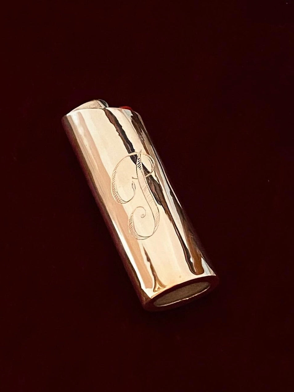 The Pedro Ventura Monogram Lighter Case Maxi Size, crafted in shiny sterling silver and engraved with the letter "J," is displayed on a dark, solid-colored surface.
